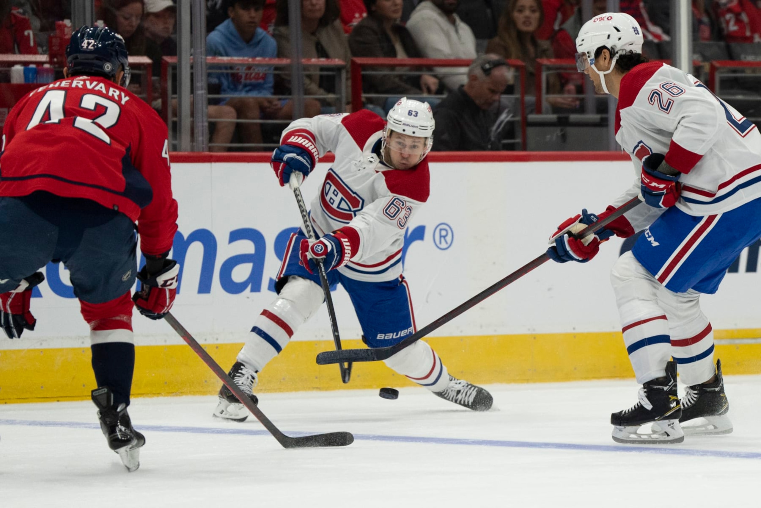 Montreal Canadiens right wing Evgenii Dadonov (63) passes the puck past defenseman Johnathan Kovacevic (26) and Washington Capitals defenseman Martin Fehervary (42) during the first period of an NHL hockey game, Saturday, Oct. 15, 2022, in Washington. (AP Photo/Jess Rapfogel) Montreal Canadiens right wing Evgenii Dadonov (63) passes the puck past defenseman Johnathan Kovacevic (26) and Washington Capitals defenseman Martin Fehervary (42) during the first period of an NHL hockey game, Saturday, Oct. 15, 2022, in Washington. (AP Photo/Jess Rapfogel)