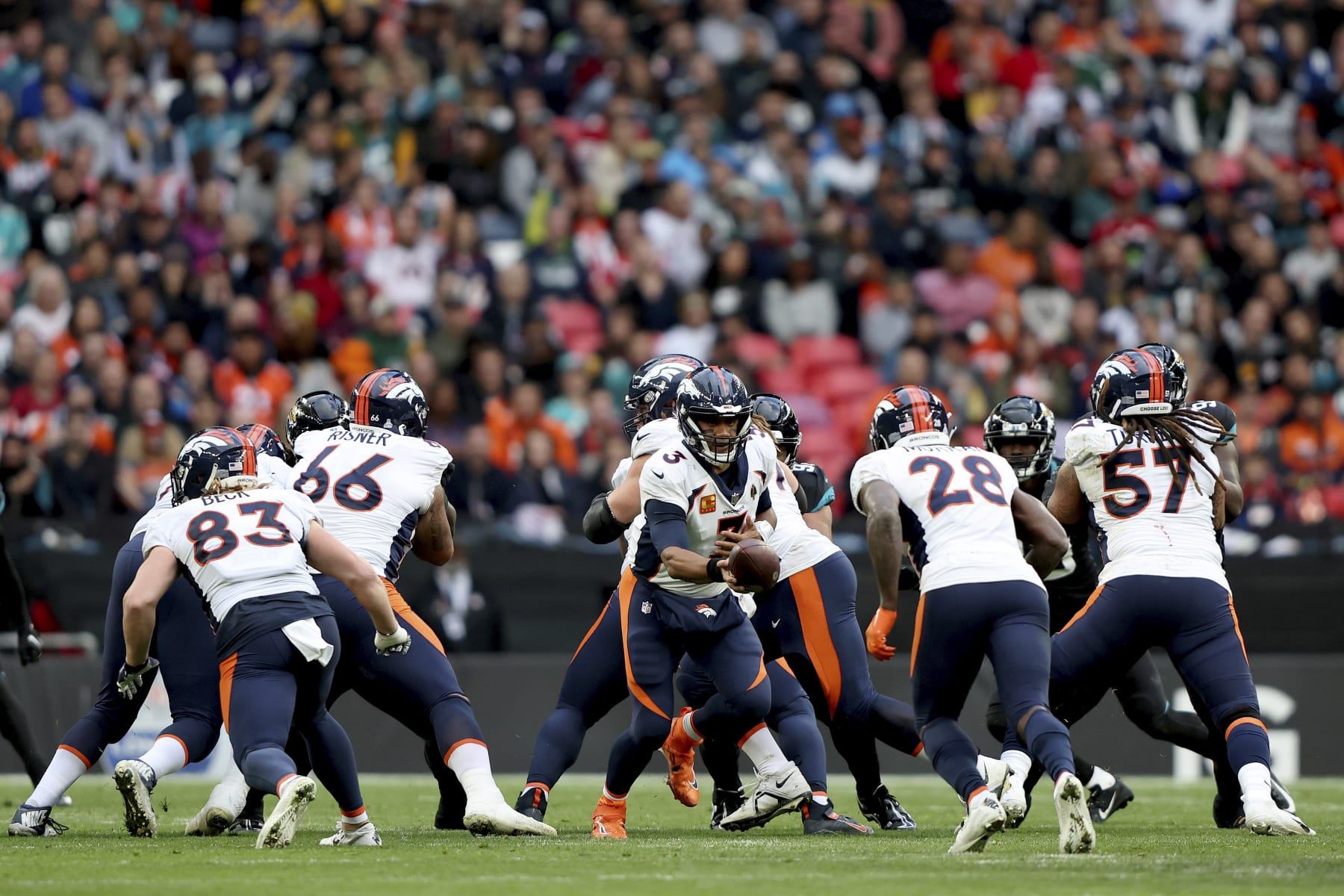 Denver Broncos quarterback Russell Wilson (3), centre, hands the ball over during the NFL football game between Denver Broncos and Jacksonville Jaguars at Wembley Stadium in London, Sunday, Oct. 30, 2022. (AP Photo/Ian Walton)