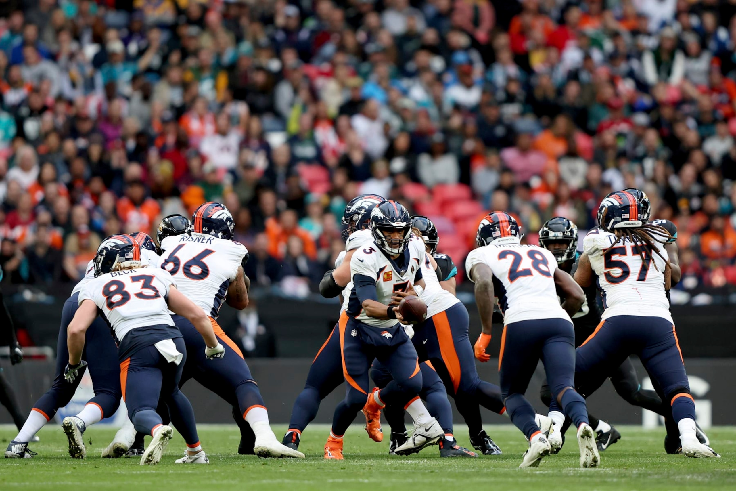 Denver Broncos quarterback Russell Wilson (3), centre, hands the ball over during the NFL football game between Denver Broncos and Jacksonville Jaguars at Wembley Stadium in London, Sunday, Oct. 30, 2022. (AP Photo/Ian Walton)
