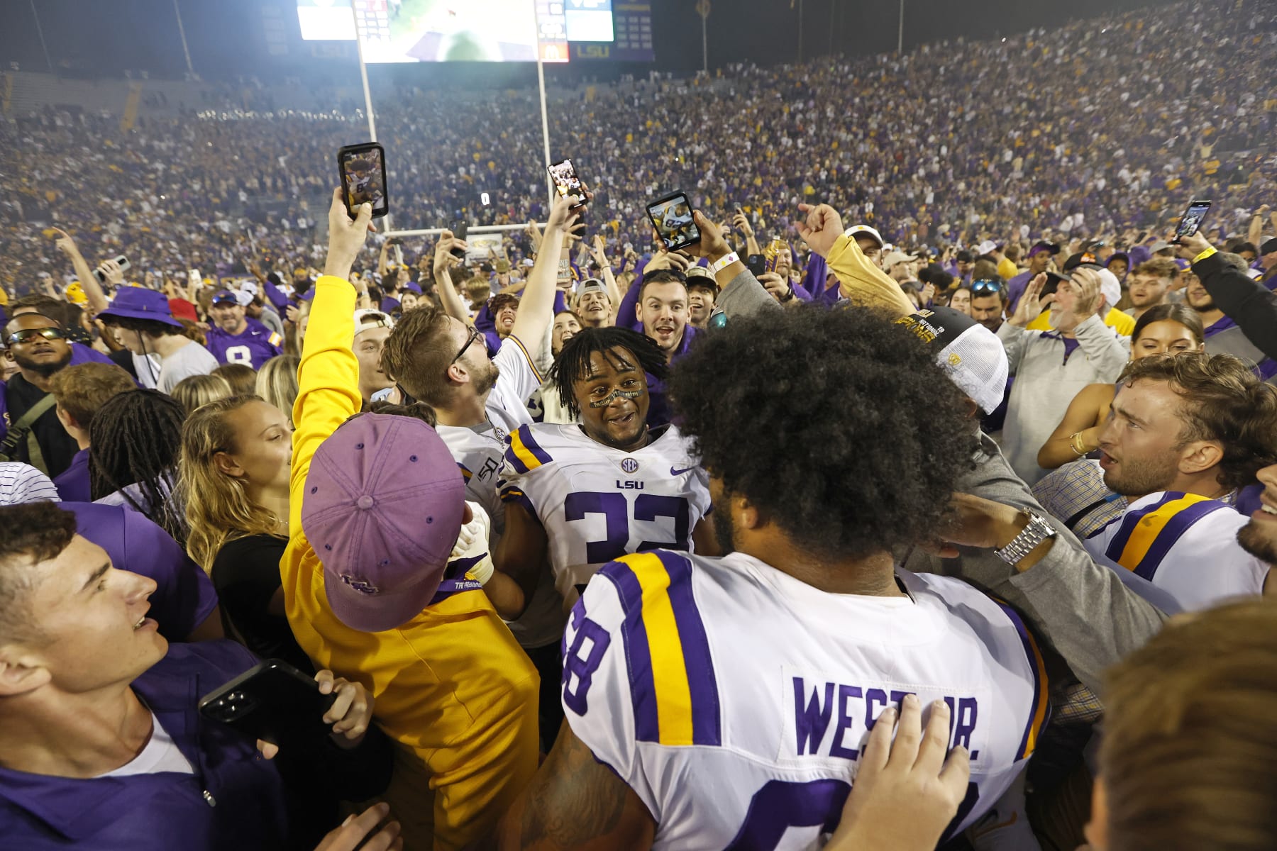 LSU offensive lineman Fitzgerald West Jr. (68) and linebacker DeMario Tolan (32) celebrate with fans who stormed the field after an NCAA college football game against Alabama in Baton Rouge, La., Saturday, Nov. 5, 2022. LSU won 32-31 in overtime. (AP Photo/Tyler Kaufman)
