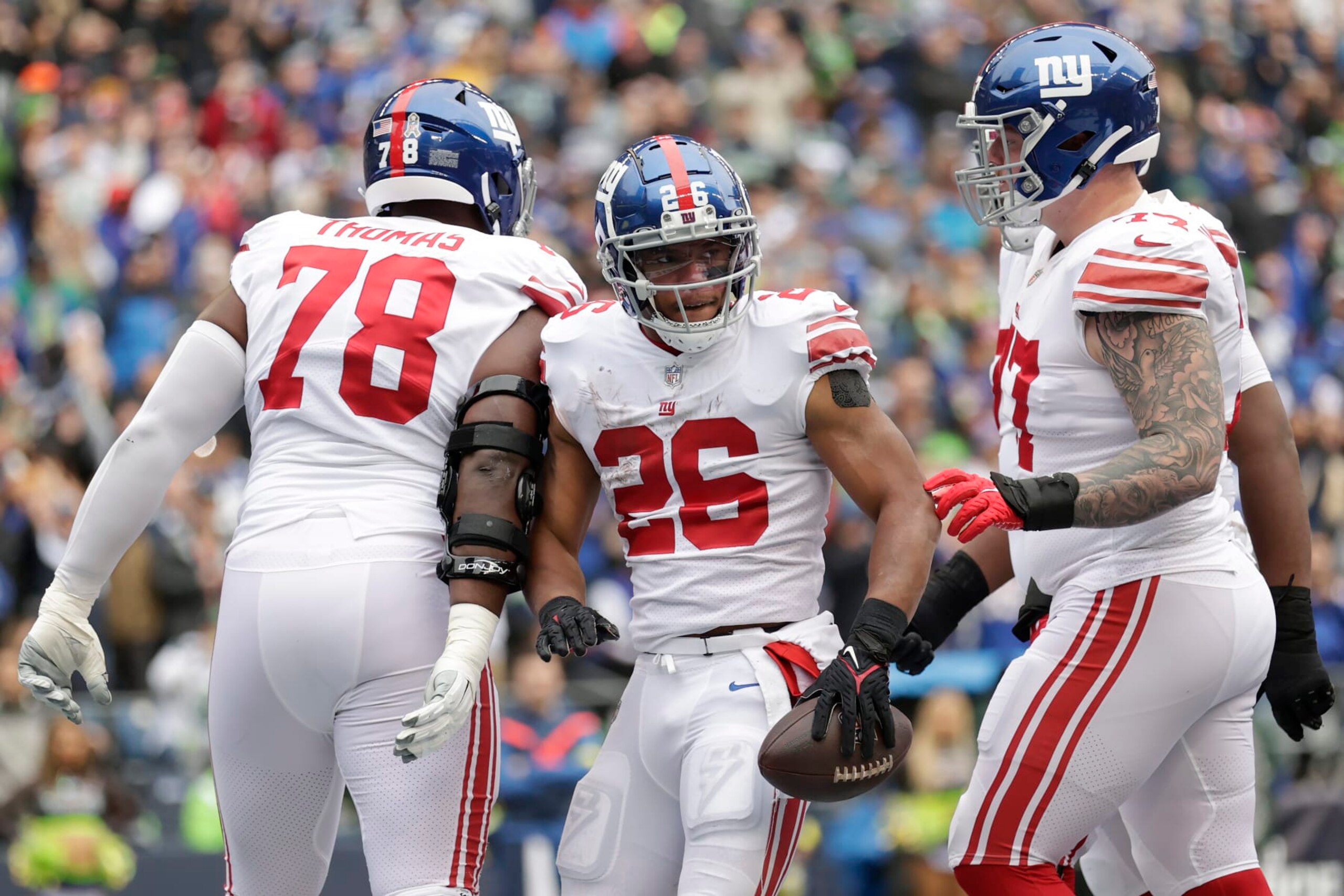 New York Giants running back Saquon Barkley (26) celebrates with offensive tackle Andrew Thomas (78) and guard Jack Anderson after scoring a touchdown against the Seattle Seahawks during the first half of an NFL football game in Seattle, Sunday, Oct. 30, 2022. (AP Photo/John Froschauer)
