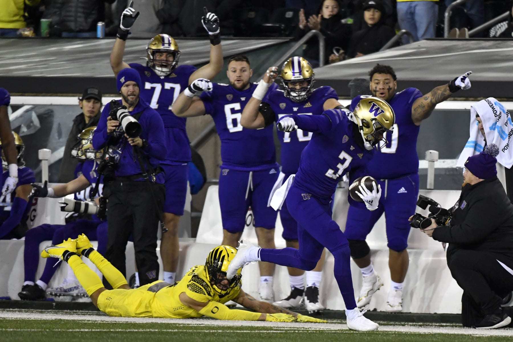 Washington wide receiver Taj Davis (3) eludes a tackle by Oregon defensive back Bennett Williams, bottom left, and heads to the end zone as teammates point the way during the second half of an NCAA college football game Saturday, Nov. 12, 2022, in Eugene, Ore. (AP Photo/Andy Nelson)