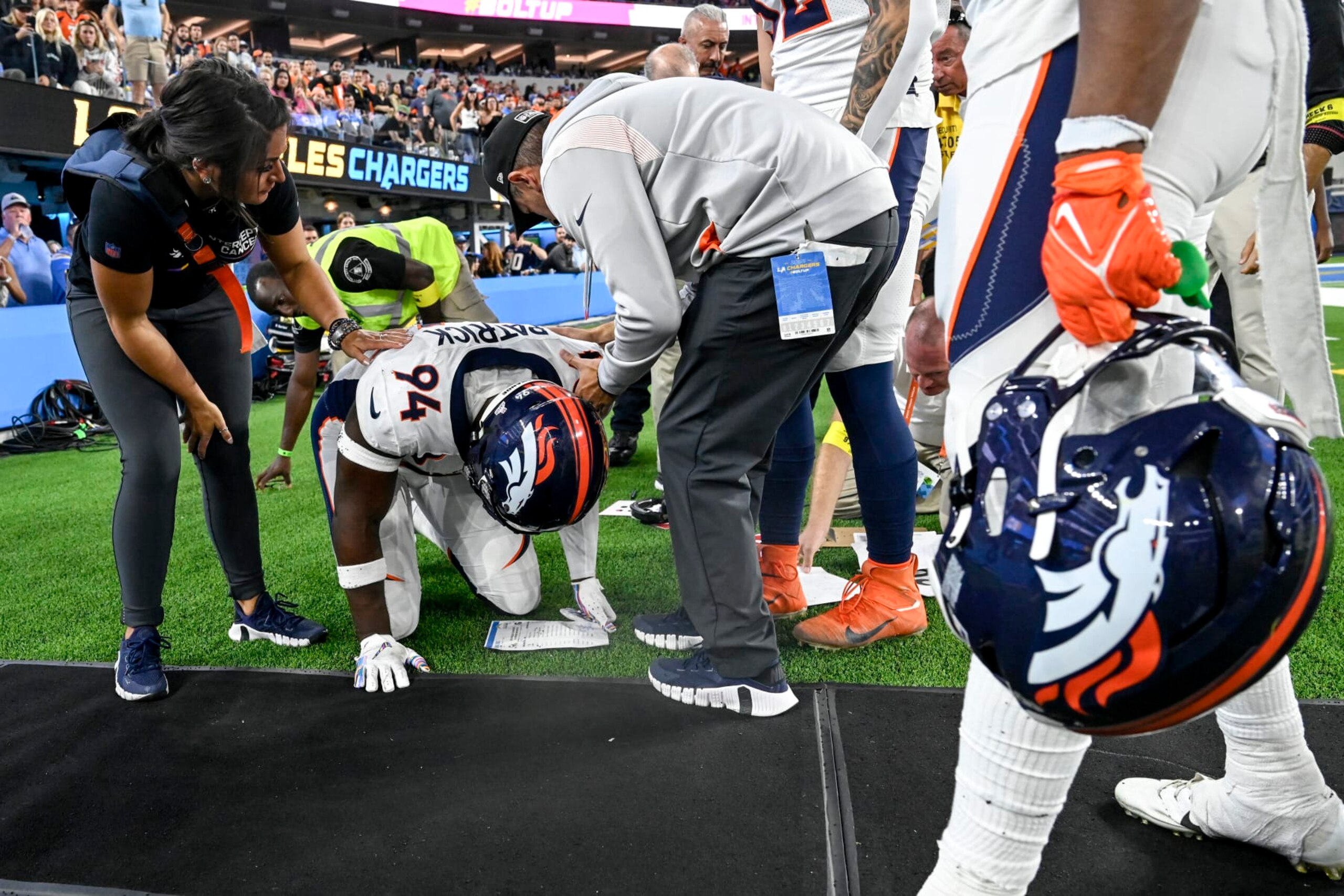 INGLEWOOD , CA - OCTOBER 17: Aaron Patrick (94) of the Denver Broncos kneels on the ground after colliding with a middle aged sideline worker during overtime of the Los Angeles Chargers 19-16 win at SoFi Stadium in Inglewood, California on Monday, October 17, 2022. The worker was quick to return to his post as team medical personnel tended to Patrick. (Photo by AAron Ontiveroz/MediaNews Group/The Denver Post via Getty Images)