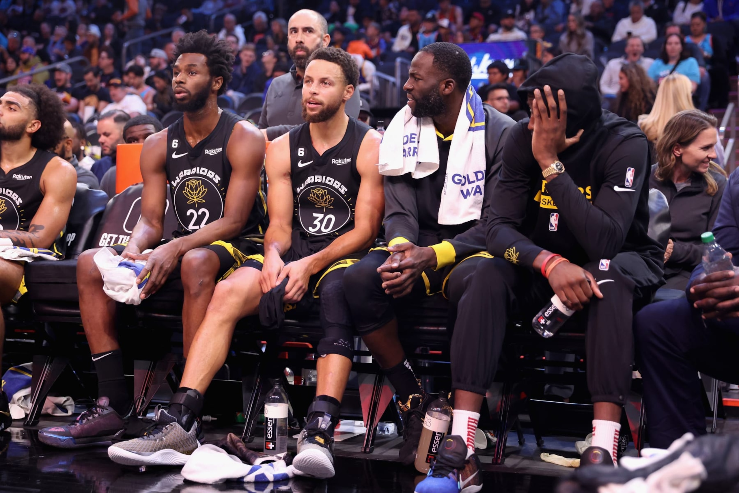 PHOENIX, ARIZONA - NOVEMBER 16:  (L-R) Andrew Wiggins #22, Stephen Curry #30, Draymond Green #23 and Jonathan Kuminga #00 of the Golden State Warriors sit on the bench during the second half of the NBA game at Footprint Center on November 16, 2022 in Phoenix, Arizona. The Suns defeated the Warriors 130-119. NOTE TO USER: User expressly acknowledges and agrees that, by downloading and or using this photograph, User is consenting to the terms and conditions of the Getty Images License Agreement.  (Photo by Christian Petersen/Getty Images)