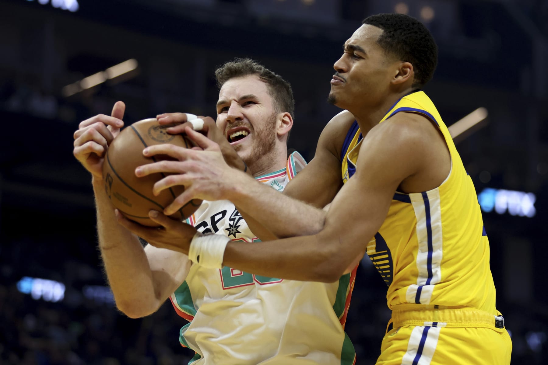 San Antonio Spurs center Jakob Poeltl, left, and Golden State Warriors guard Jordan Poole, right, battle for a rebound during the first half of an NBA basketball game in San Francisco, Sunday, March. 20, 2022. (AP Photo/Jed Jacobsohn)