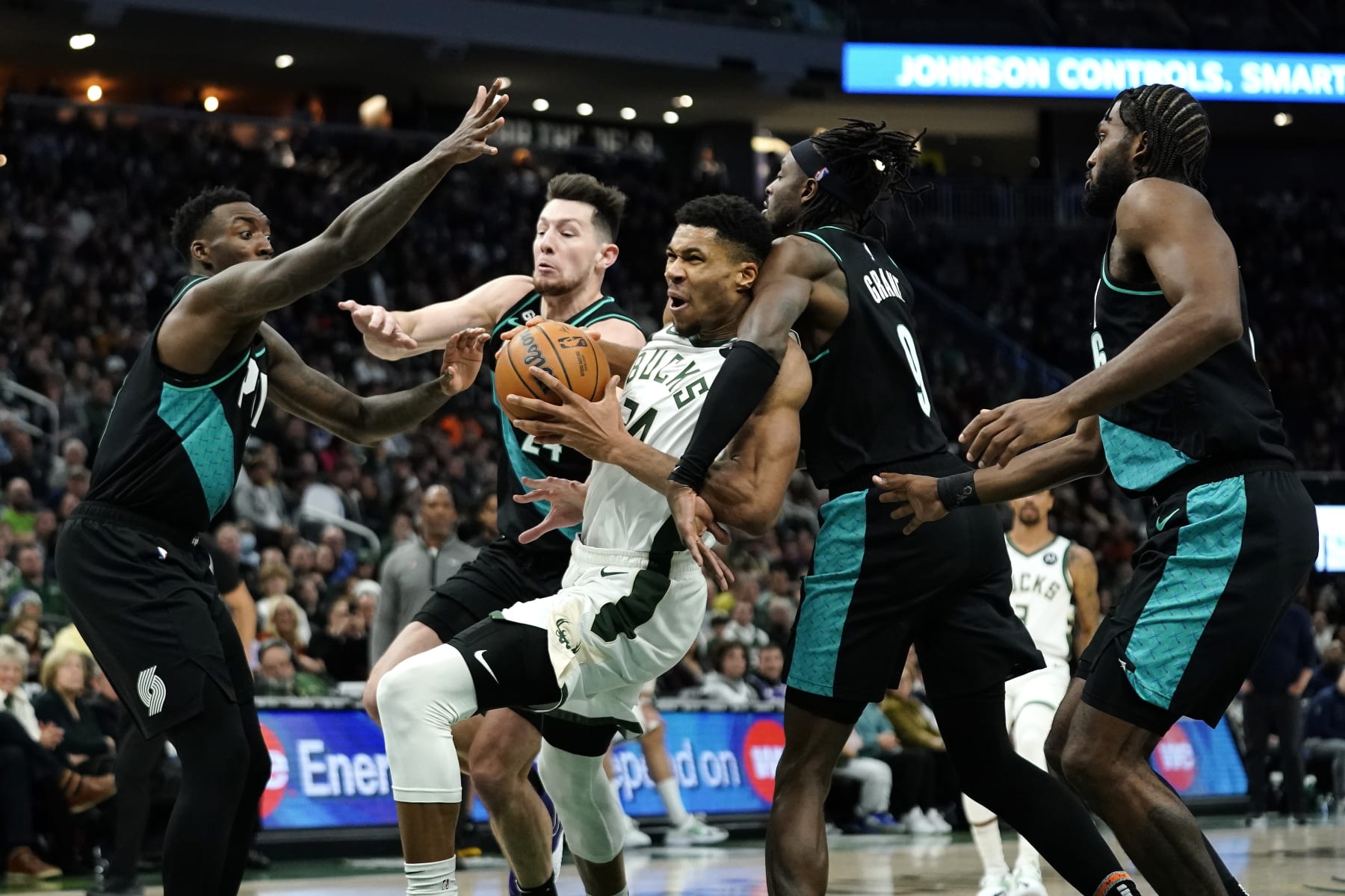 Milwaukee Bucks' Giannis Antetokounmpo (34), center, is fouled as drives to the basket against multiple Portland Trail Blazers defenders during the second half of an NBA basketball game Monday, Nov. 21, 2022, in Milwaukee. (AP Photo/Aaron Gash)