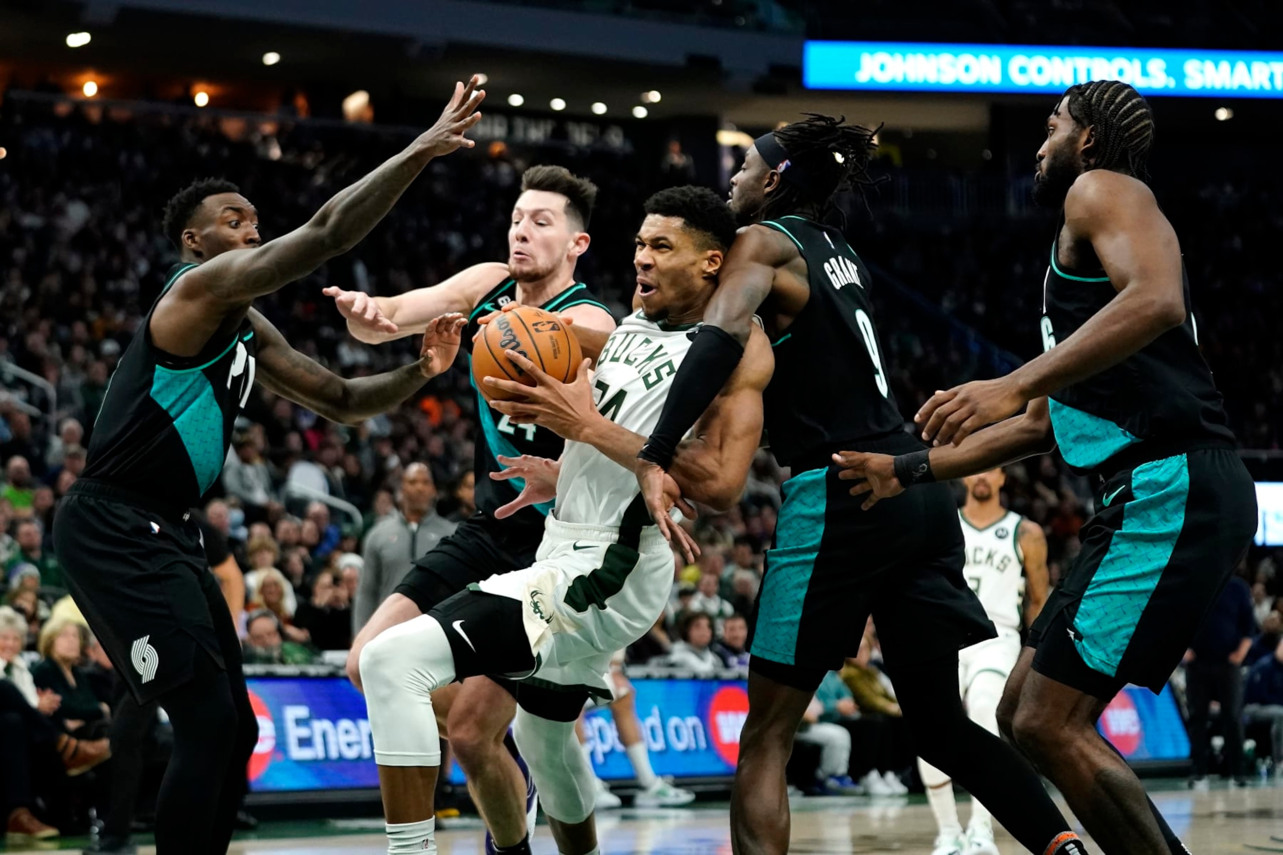 Milwaukee Bucks' Giannis Antetokounmpo (34), center, is fouled as drives to the basket against multiple Portland Trail Blazers defenders during the second half of an NBA basketball game Monday, Nov. 21, 2022, in Milwaukee. (AP Photo/Aaron Gash)