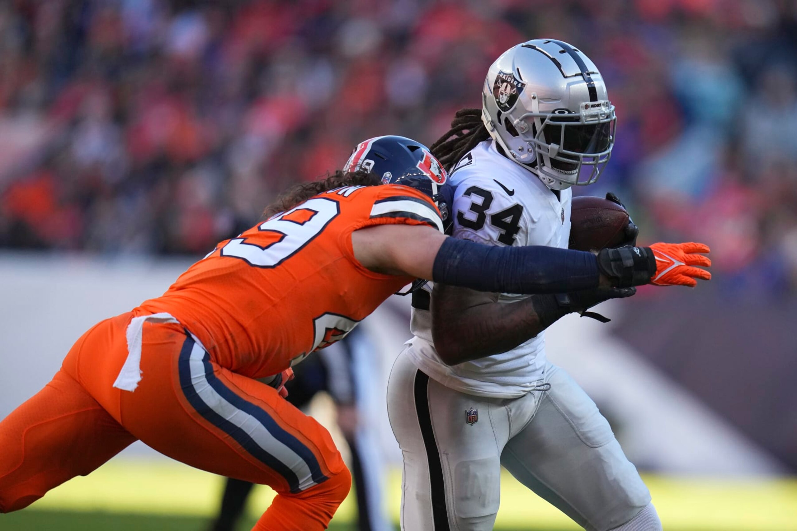 Las Vegas Raiders running back Brandon Bolden (34) runs against Denver Broncos linebacker Alex Singleton during the first half of an NFL football game in Denver, Sunday, Nov. 20, 2022. (AP Photo/Jack Dempsey)