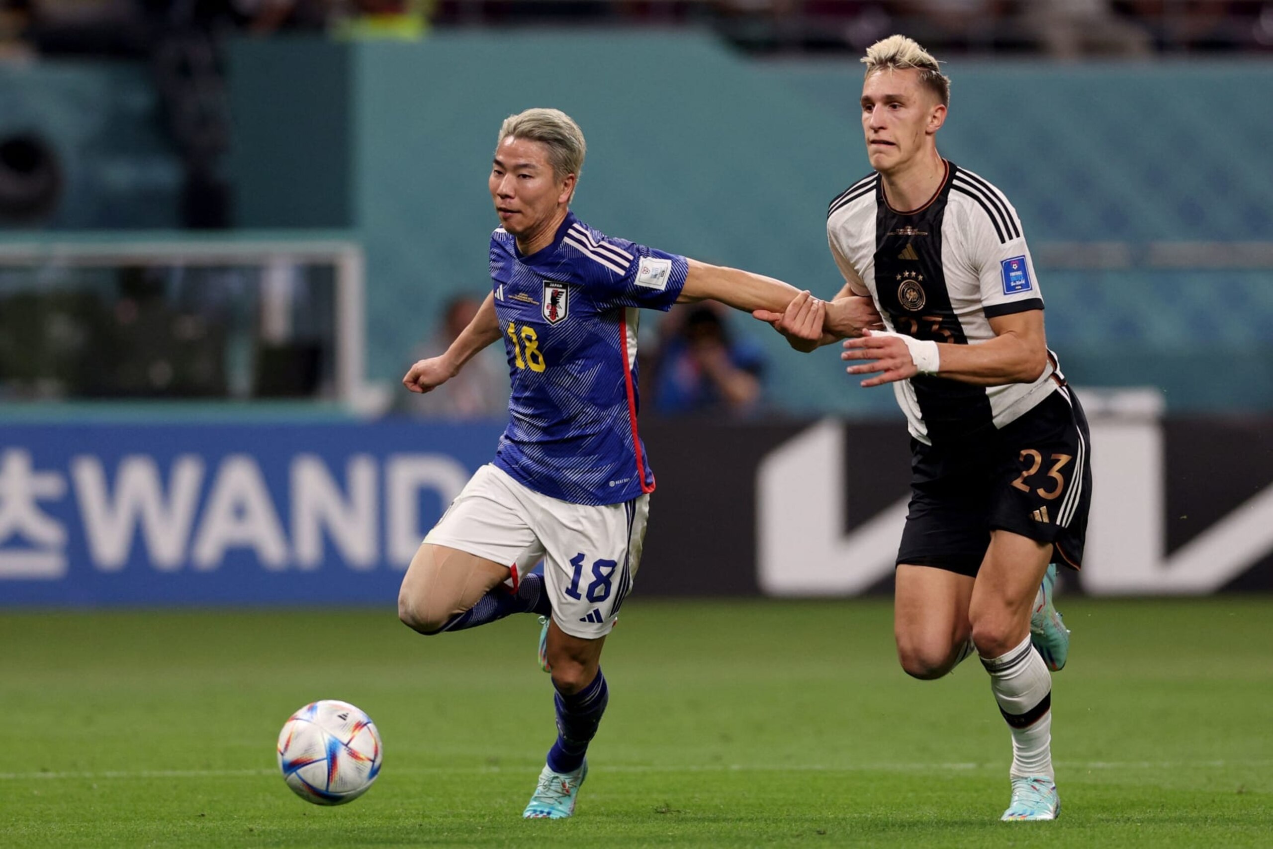 Germany's defender #23 Nico Schlotterbeck (R) fights for the ball with Japan's forward #18 Takuma Asano during the Qatar 2022 World Cup Group E football match between Germany and Japan at the Khalifa International Stadium in Doha on November 23, 2022. (Photo by Adrian DENNIS / AFP) (Photo by ADRIAN DENNIS/AFP via Getty Images)