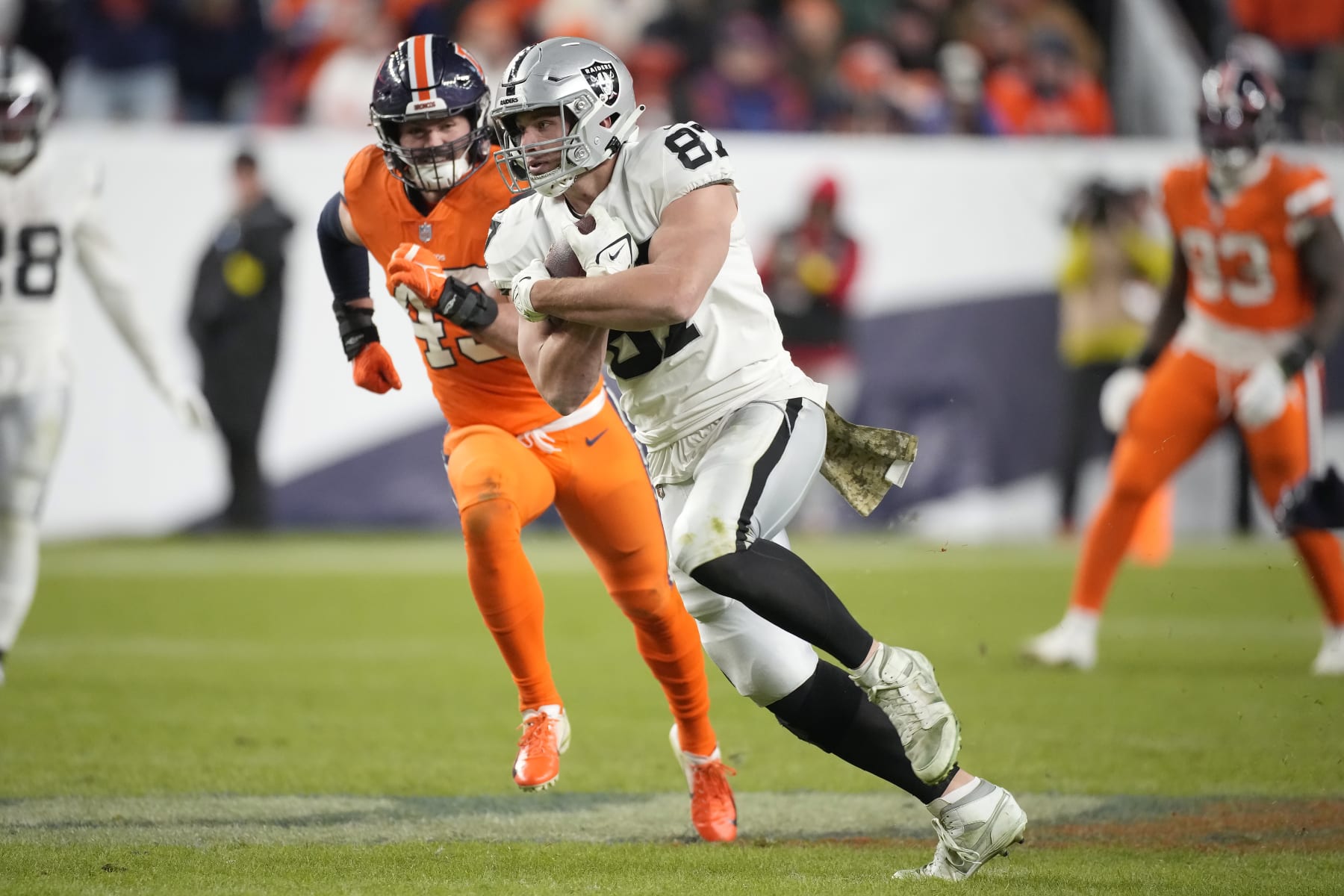 Las Vegas Raiders tight end Foster Moreau (87) runs against Denver Broncos linebacker Alex Singleton during overtime of an NFL football game in Denver, Sunday, Nov. 20, 2022. (AP Photo/David Zalubowski)