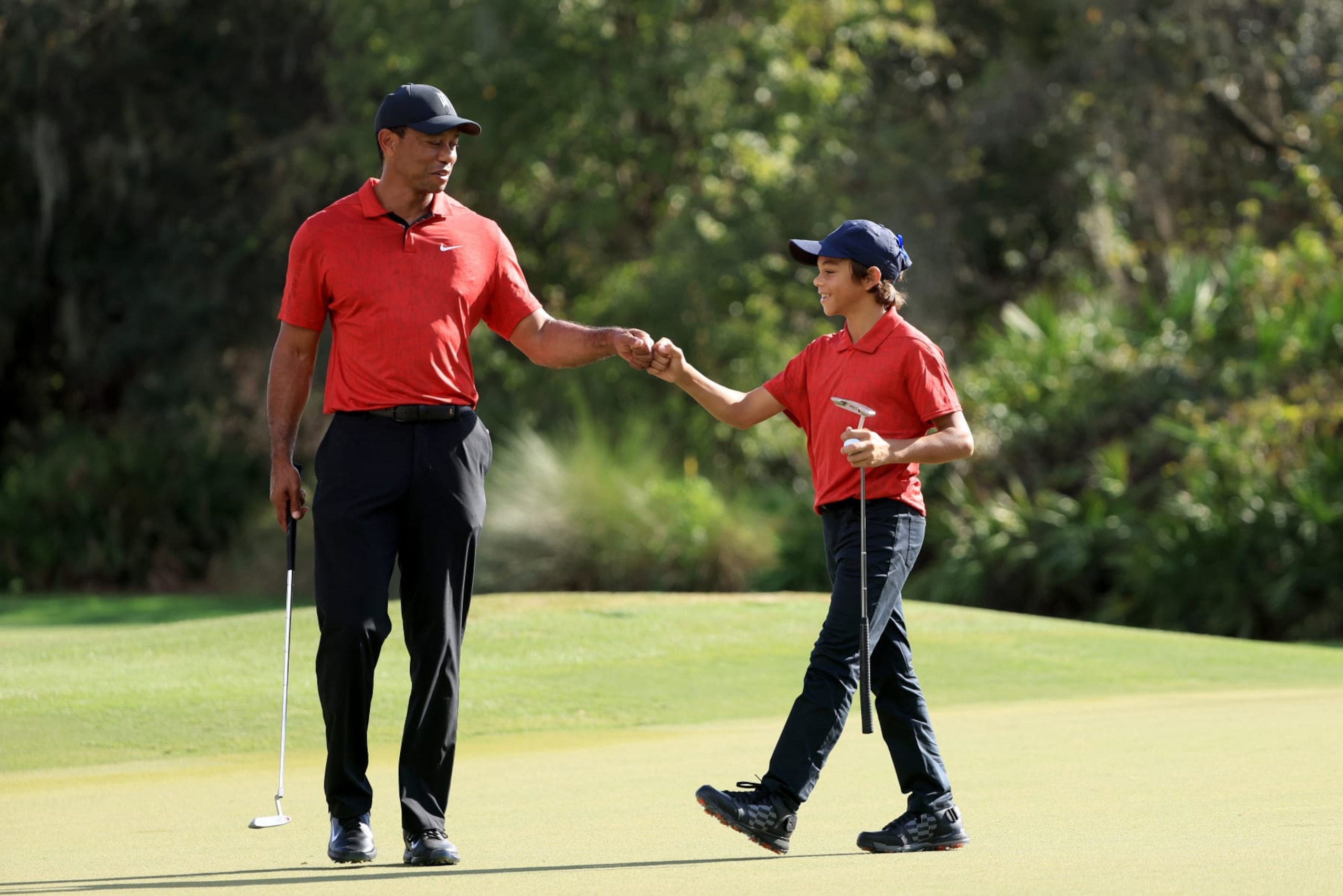 ORLANDO, FLORIDA - DECEMBER 19: Tiger Woods and Charlie Woods celebrate a birdie on the 12th hole during the final round of the PNC Championship at the Ritz Carlton Golf Club Grande Lakes   on December 19, 2021 in Orlando, Florida. (Photo by Sam Greenwood/Getty Images)