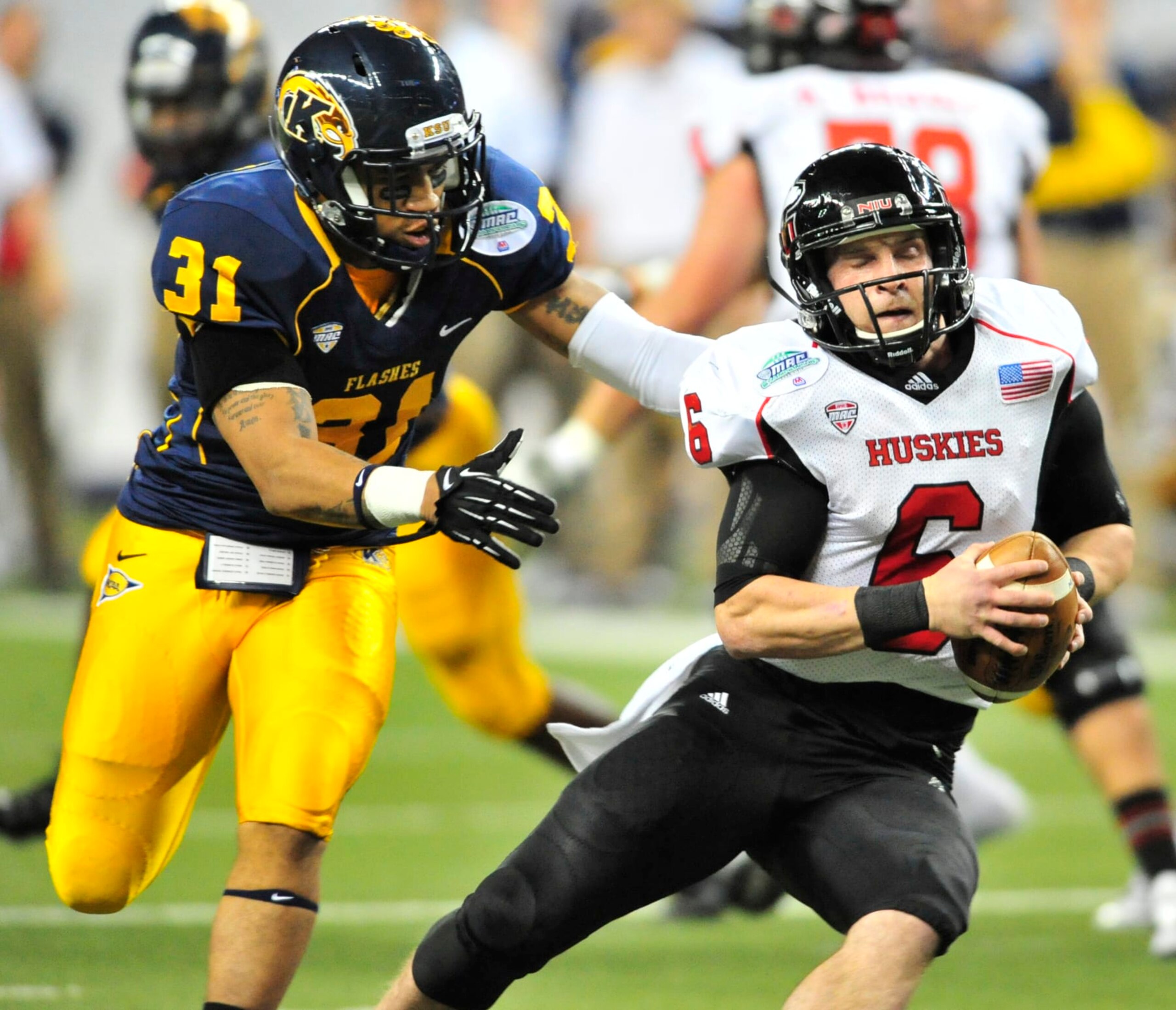 DETROIT, MICHIGAN - NOVEMBER 30, 2012: Quarterback Jordan Lynch #6 of the Northern Illinois Huskies spins away from a tackle from defensive back DeVante' Strickland #31 of the Kent State Golden Flashes during a game against the Kent State Golden Flashes at Ford Field in Detroit, Michigan. Northern Illinois won 44-37. (Photo by David Dermer/Diamond Images/Getty Images)