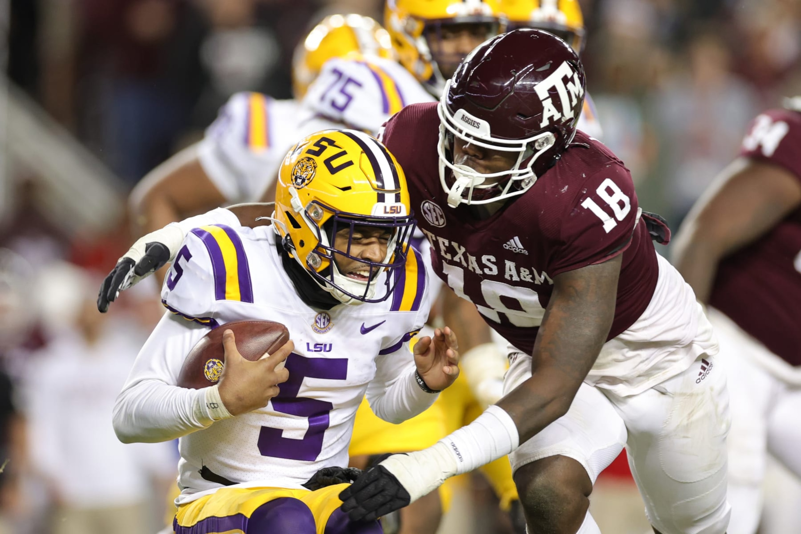 COLLEGE STATION, TEXAS - NOVEMBER 26: Jayden Daniels #5 of the LSU Tigers rushes from pressure from LT Overton #18 of the Texas A&M Aggies during the second half at Kyle Field on November 26, 2022 in College Station, Texas. (Photo by Carmen Mandato/Getty Images)