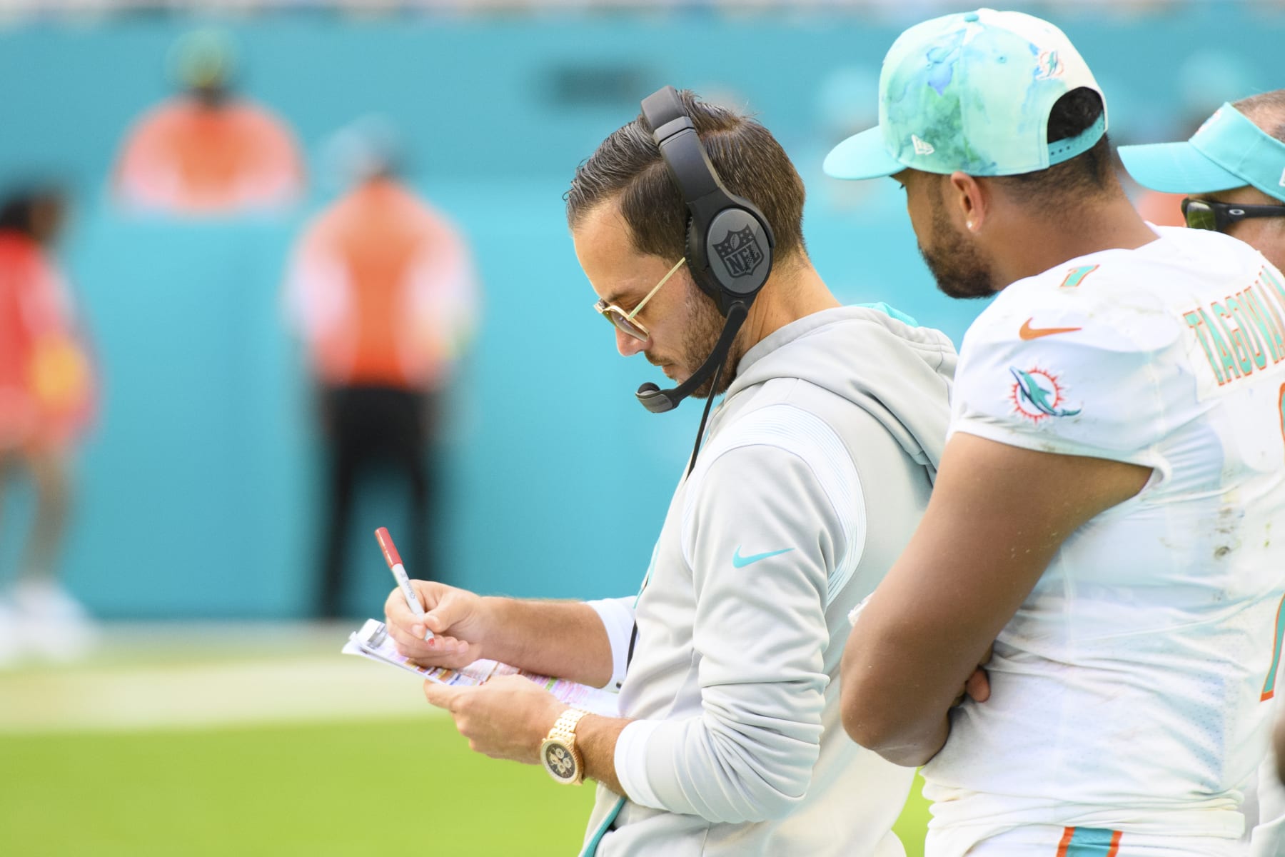 Miami Dolphins quarterback Tua Tagovailoa (1) watches Miami Dolphins head coach Mike McDaniel make notes on the sidelines during an NFL football game between the Houston Texans and the Miami Dolphins, Sunday, Nov. 27, 2022, in Miami Gardens, Fla. (AP Photo/Doug Murray)
