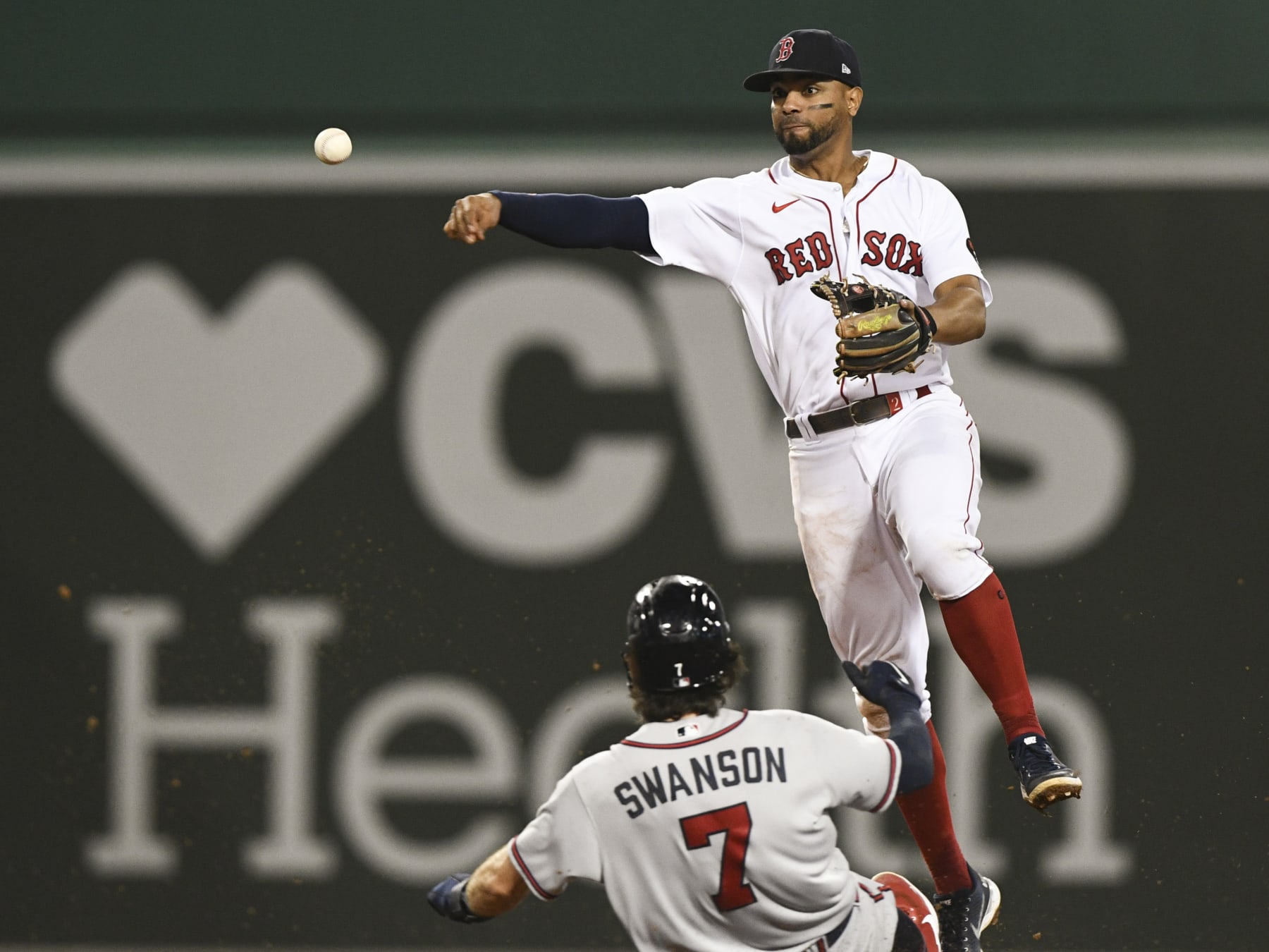 BOSTON, MASSACHUSETTS - AUGUST 10: Xander Bogaerts #2 of the Boston Red Sox throws to first base over Dansby Swanson #7 of the Atlanta Braves to make a double play during the ninth inning at Fenway Park on August 10, 2022 in Boston, Massachusetts. (Photo by Brian Fluharty/Getty Images)