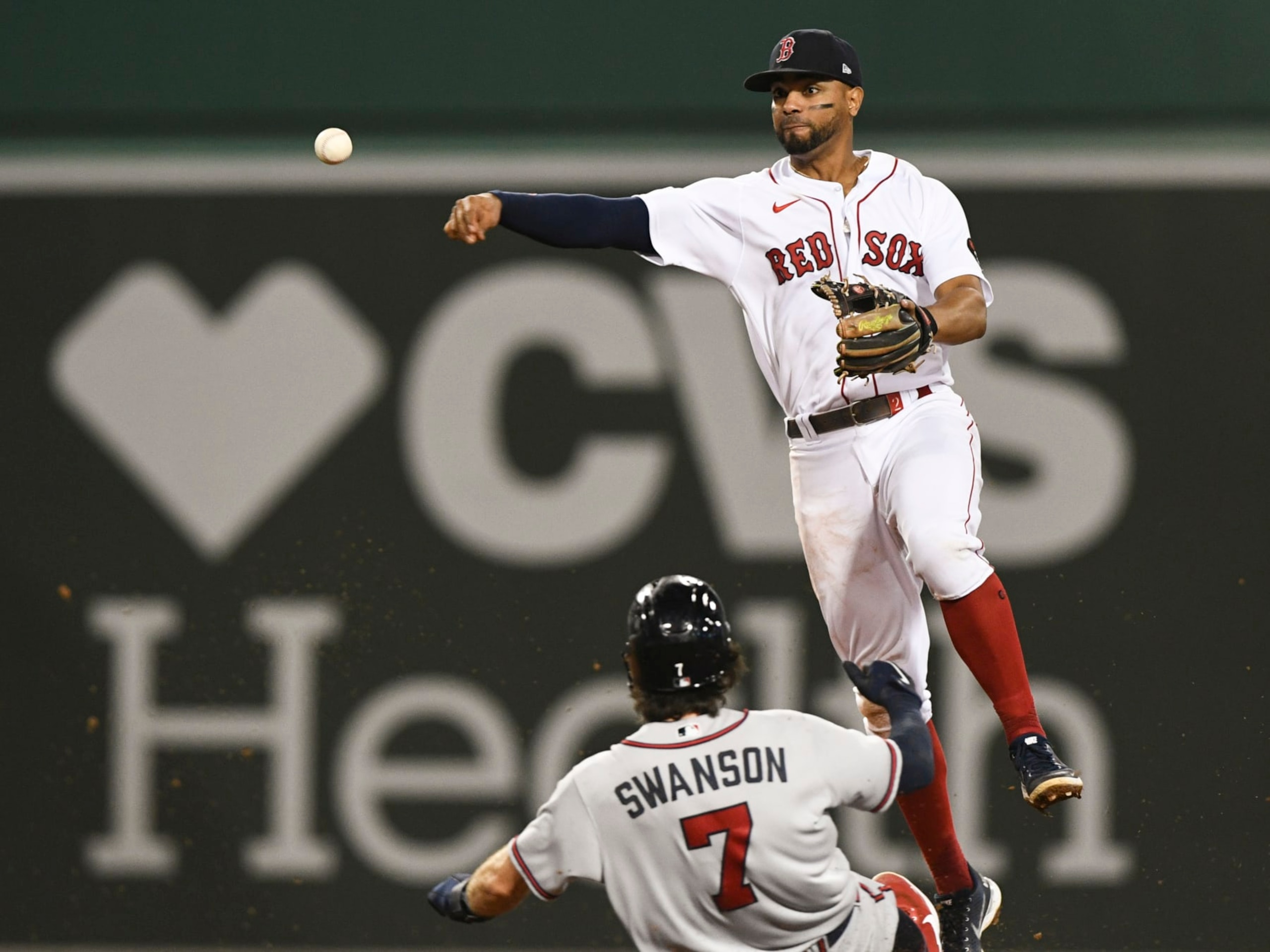 BOSTON, MASSACHUSETTS - AUGUST 10: Xander Bogaerts #2 of the Boston Red Sox throws to first base over Dansby Swanson #7 of the Atlanta Braves to make a double play during the ninth inning at Fenway Park on August 10, 2022 in Boston, Massachusetts. (Photo by Brian Fluharty/Getty Images)