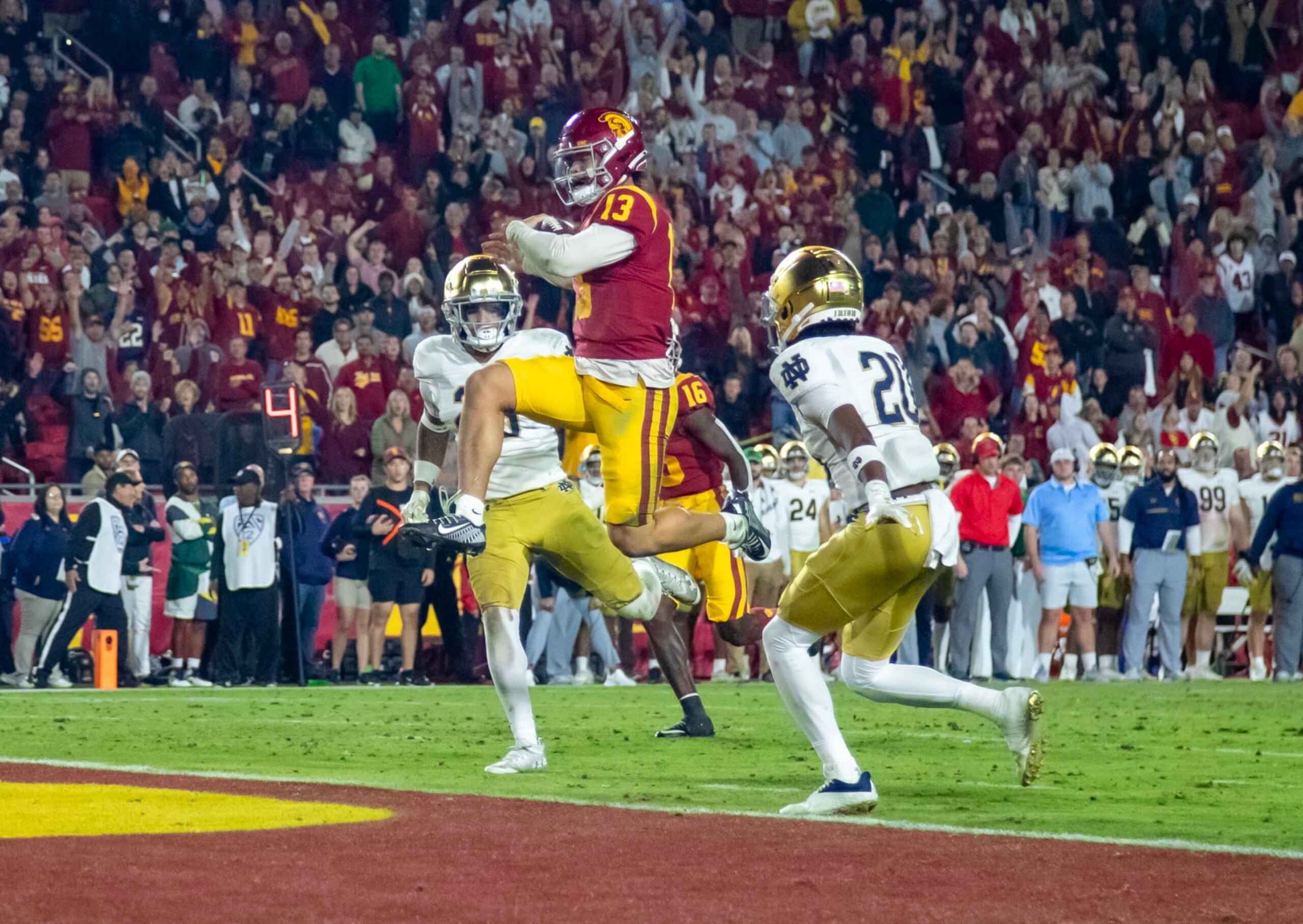 LOS ANGELES, CA - NOVEMBER 26, 2022: USC Trojans quarterback Caleb Williams (13) scores his third touchdown of the game against Notre Dame Fighting Irish safety Xavier Watts (26) and Notre Dame Fighting Irish cornerback Benjamin Morrison (20) in the fourth quarter at the Coliseum on November 26, 2022 in Los Angeles, California.(Gina Ferazzi / Los Angeles Times via Getty Images)