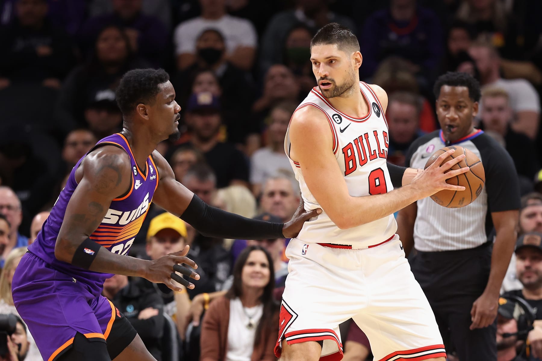 PHOENIX, ARIZONA - NOVEMBER 30: Nikola Vucevic #9 of the Chicago Bulls handles the ball against Deandre Ayton #22 of the Phoenix Suns during the first half of the NBA game at Footprint Center on November 30, 2022 in Phoenix, Arizona. The Suns defeated the Bulls 132-113. NOTE TO USER: User expressly acknowledges and agrees that, by downloading and or using this photograph, User is consenting to the terms and conditions of the Getty Images License Agreement. (Photo by Christian Petersen/Getty Images)
