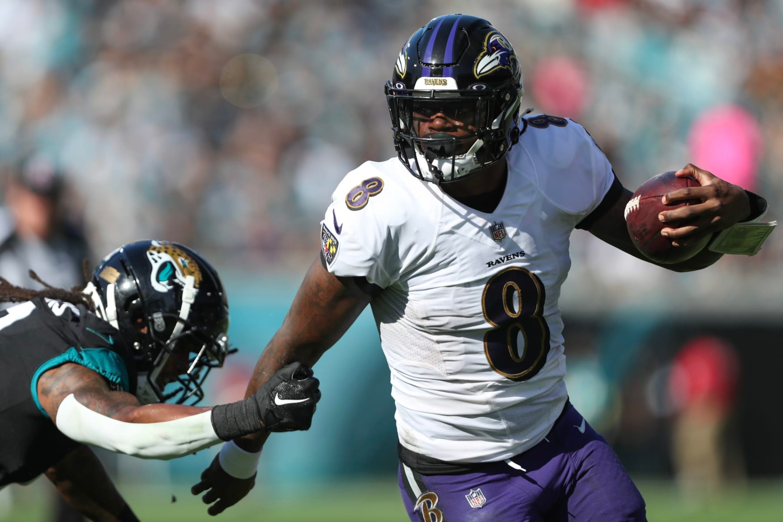 JACKSONVILLE, FLORIDA - NOVEMBER 27: Lamar Jackson #8 of the Baltimore Ravens carries the ball defended by Rayshawn Jenkins #2 of the Jacksonville Jaguars during the first half at TIAA Bank Field on November 27, 2022 in Jacksonville, Florida. (Photo by Courtney Culbreath/Getty Images)