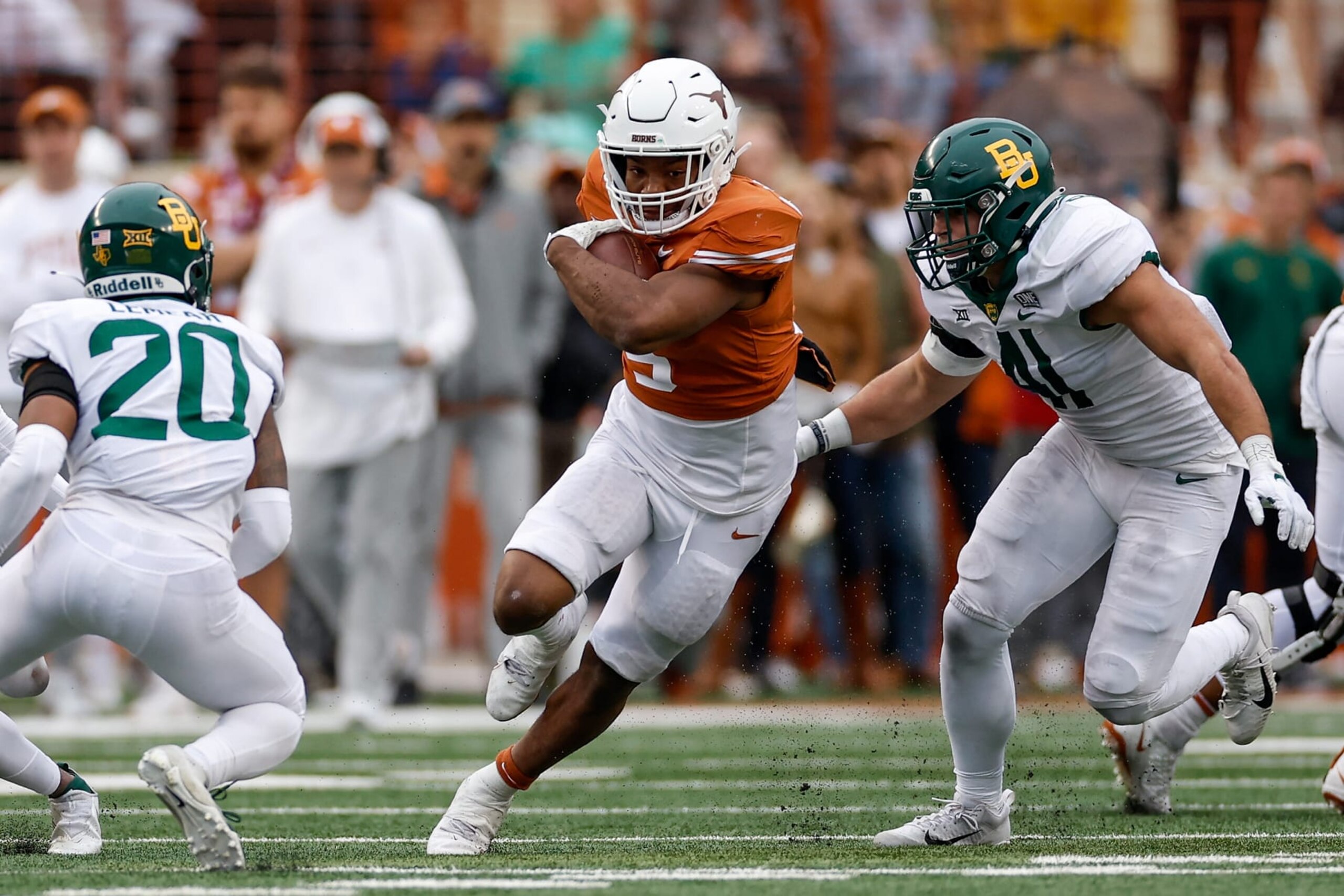 AUSTIN, TEXAS - NOVEMBER 25: Bijan Robinson #5 of the Texas Longhorns runs between Brooks Miller #41 of the Baylor Bears and Devin Lemear #20 in the fourth quarter at Darrell K Royal-Texas Memorial Stadium on November 25, 2022 in Austin, Texas. (Photo by Tim Warner/Getty Images)