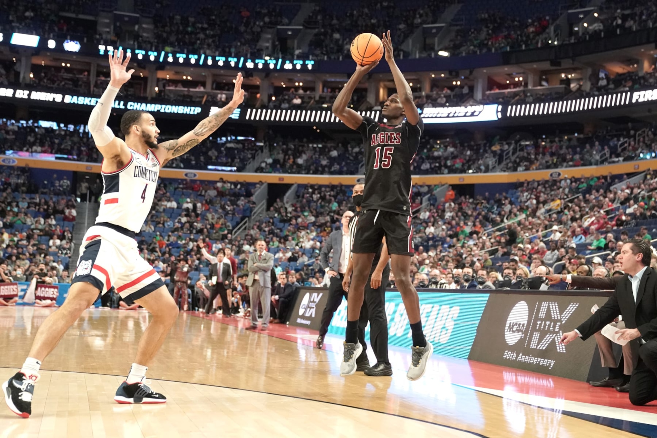 BUFFALO, NEW YORK - MARCH 17:  Mike Peake #15 of the New Mexico State Aggies takes a jump shot over Tyrese Martin #4 of the Connecticut Huskies during the first round game of the 2022 NCAA Men's Basketball Tournament at KeyBank Center on March 17, 2022 in Buffalo, New York.  (Photo by Mitchell Layton/Getty Images)