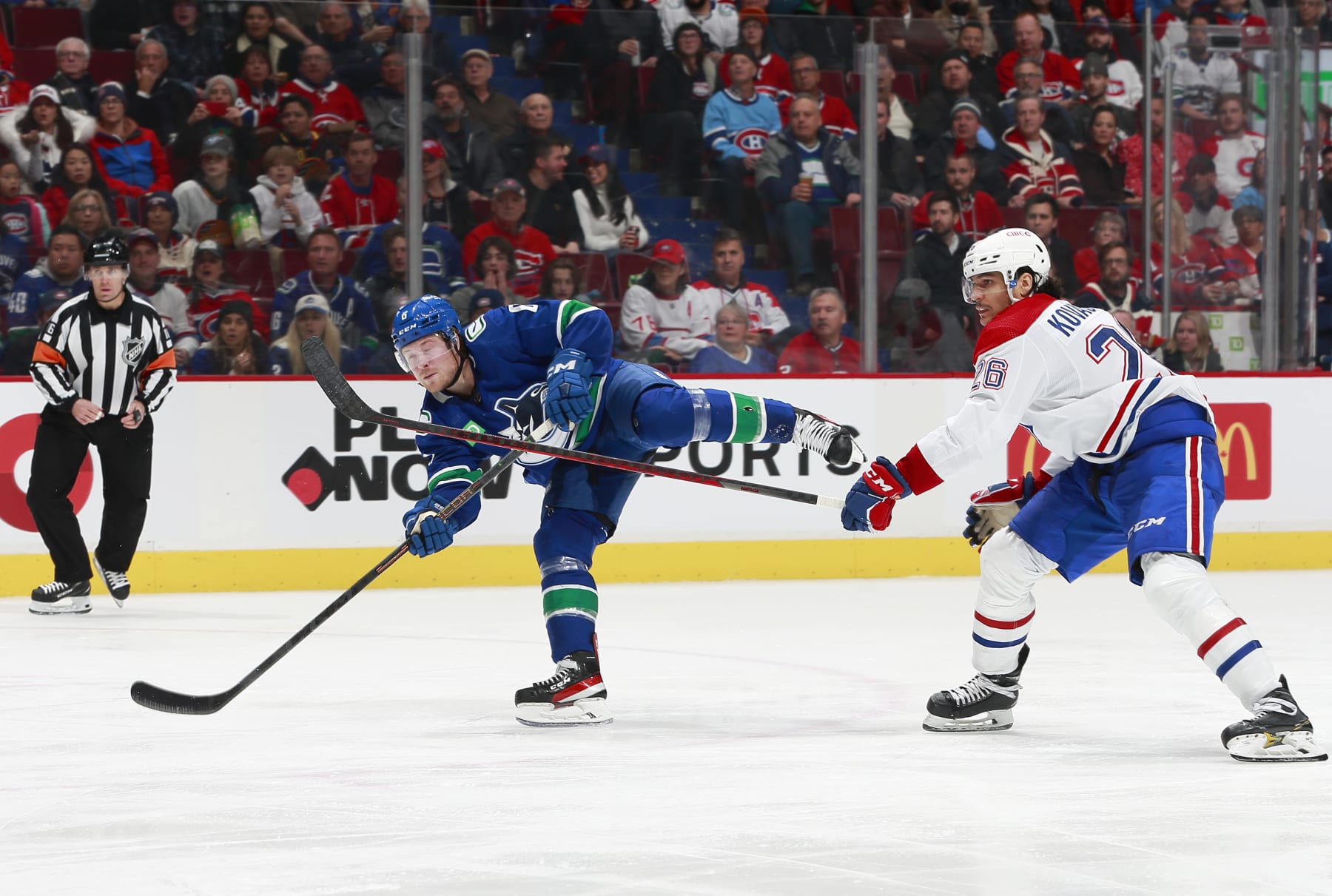 VANCOUVER, CANADA - DECEMBER 5: Johnathan Kovacevic #26 of the Montréal Canadiens looks on as Brock Boeser #6 of the Vancouver Canucks takes a shot during their NHL game at Rogers Arena December 5, 2022 in Vancouver, British Columbia, Canada.  (Photo by Jeff Vinnick/NHLI via Getty Images)