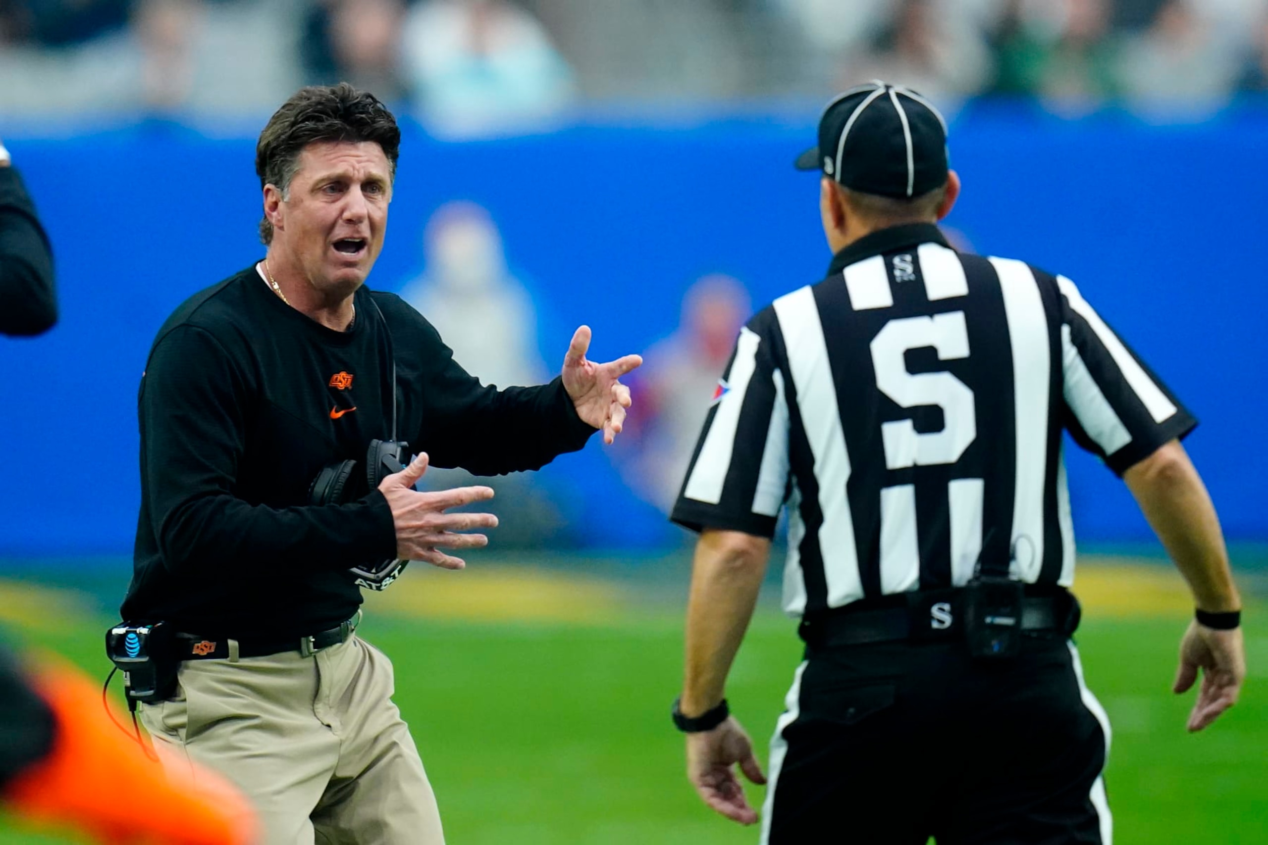FILE - Oklahoma State head coach Mike Gundy, left, argues a call with an official during the first half of the Fiesta Bowl NCAA college football game against Notre Dame, Jan. 1, 2022, in Glendale, Ariz. Oklahoma State has boosted Gundy’s salary to $7.5 million for the 2022 calendar year. (AP Photo/Ross D. Franklin, File)