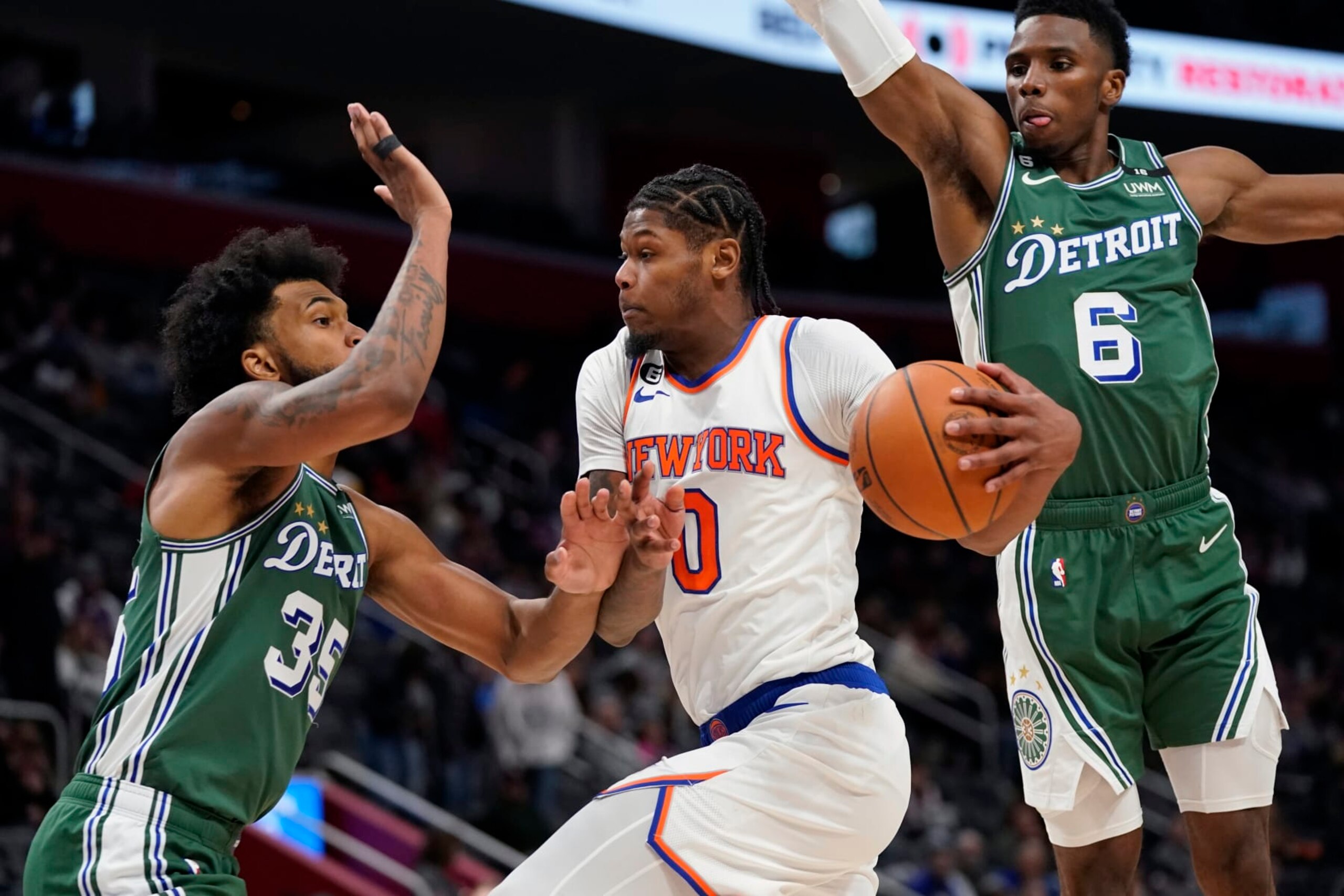 New York Knicks forward Cam Reddish (0) passes as Detroit Pistons forward Marvin Bagley III (35) and guard Hamidou Diallo (6) defend during the second half of an NBA basketball game, Tuesday, Nov. 29, 2022, in Detroit. (AP Photo/Carlos Osorio)