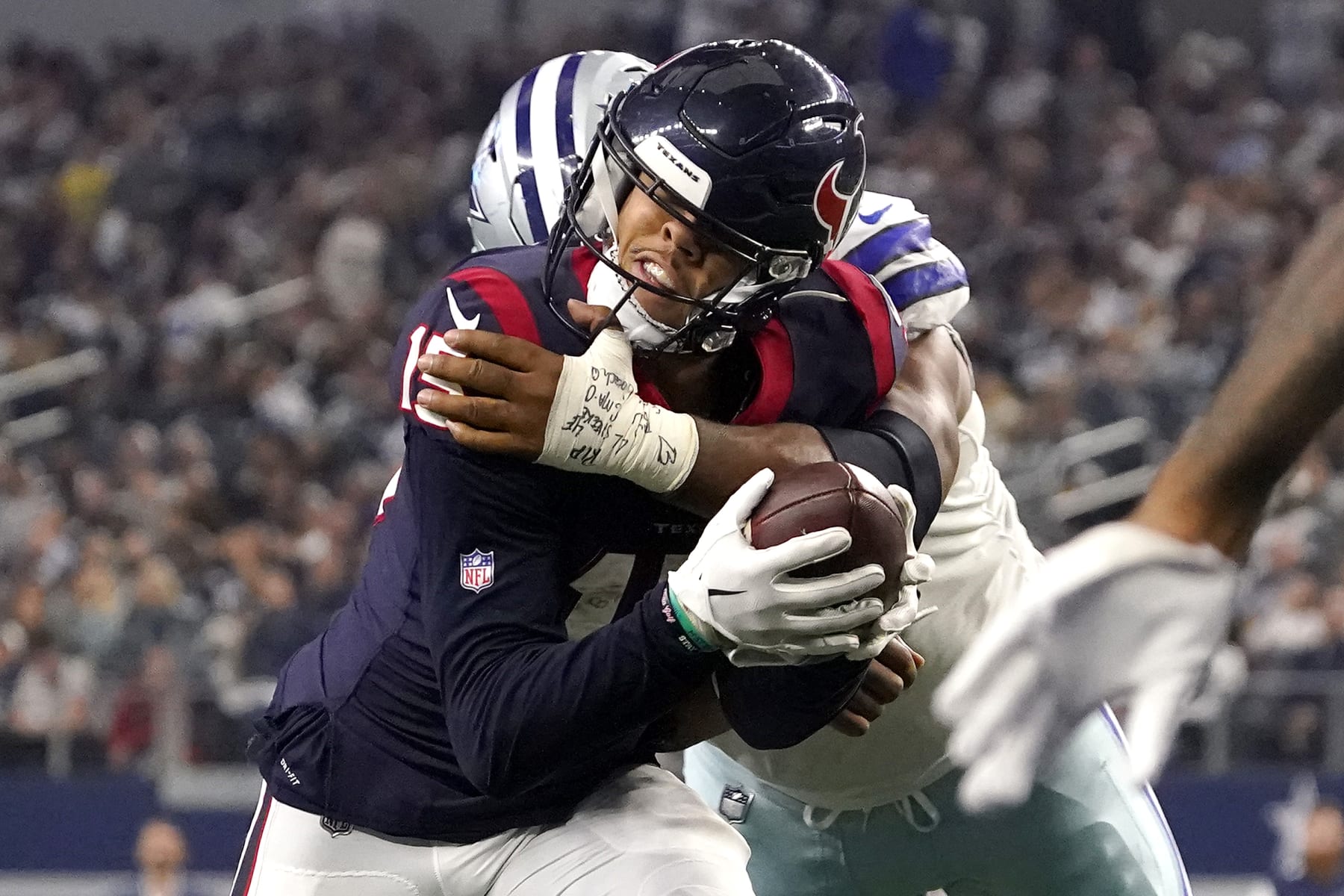 ARLINGTON, TEXAS - DECEMBER 11: Chris Moore #15 of the Houston Texans gets hit by Carlos Watkins #91 of the Dallas Cowboys in the fourth quarter of a game AT&T Stadium on December 11, 2022 in Arlington, Texas. (Photo by Sam Hodde/Getty Images)