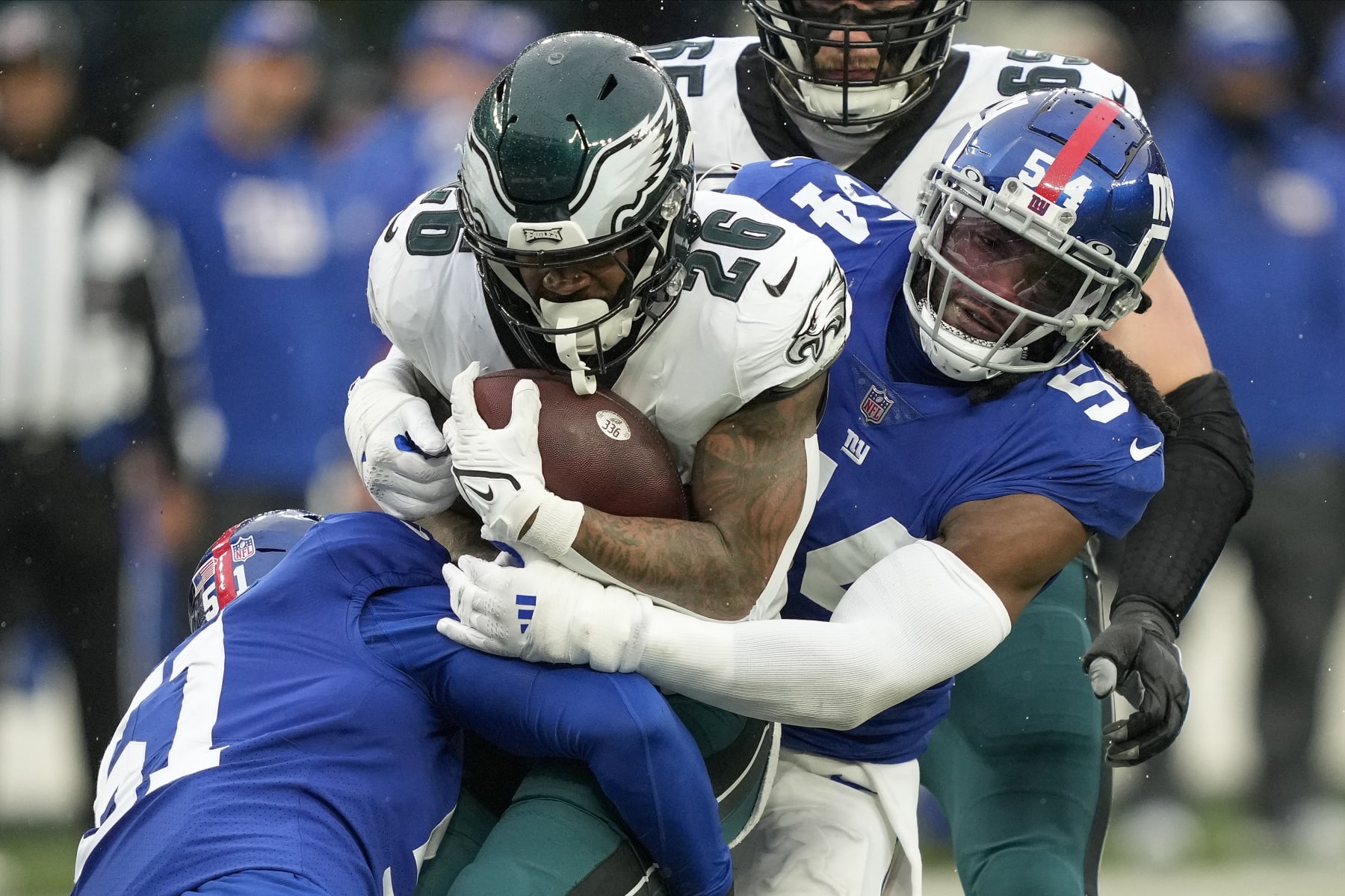 Philadelphia Eagles running back Miles Sanders (26) is tackled by New York Giants linebacker Jaylon Smith (54) =and linebacker Azeez Ojulari (51) during the second quarter of an NFL football game, Sunday, Dec. 11, 2022, in East Rutherford, N.J. (AP Photo/John Minchillo)