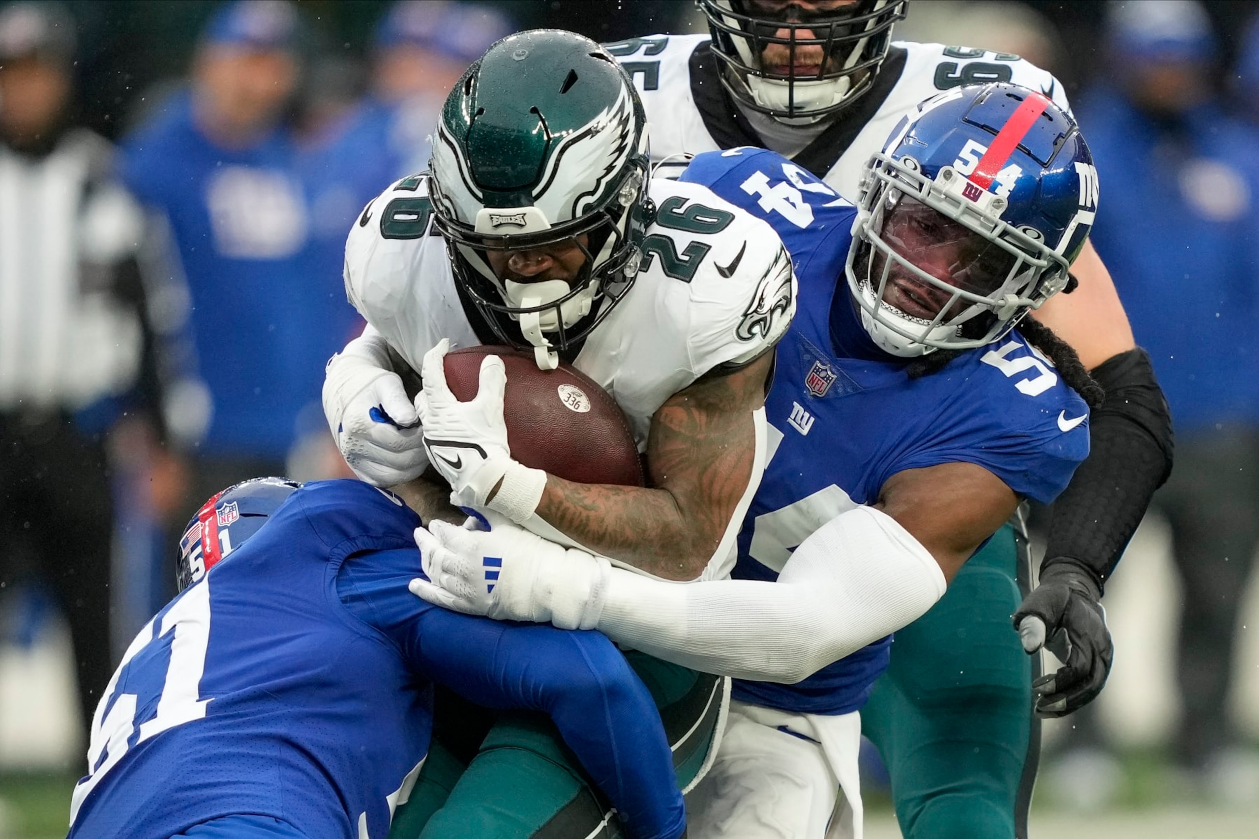 Philadelphia Eagles running back Miles Sanders (26) is tackled by New York Giants linebacker Jaylon Smith (54) =and linebacker Azeez Ojulari (51) during the second quarter of an NFL football game, Sunday, Dec. 11, 2022, in East Rutherford, N.J. (AP Photo/John Minchillo)