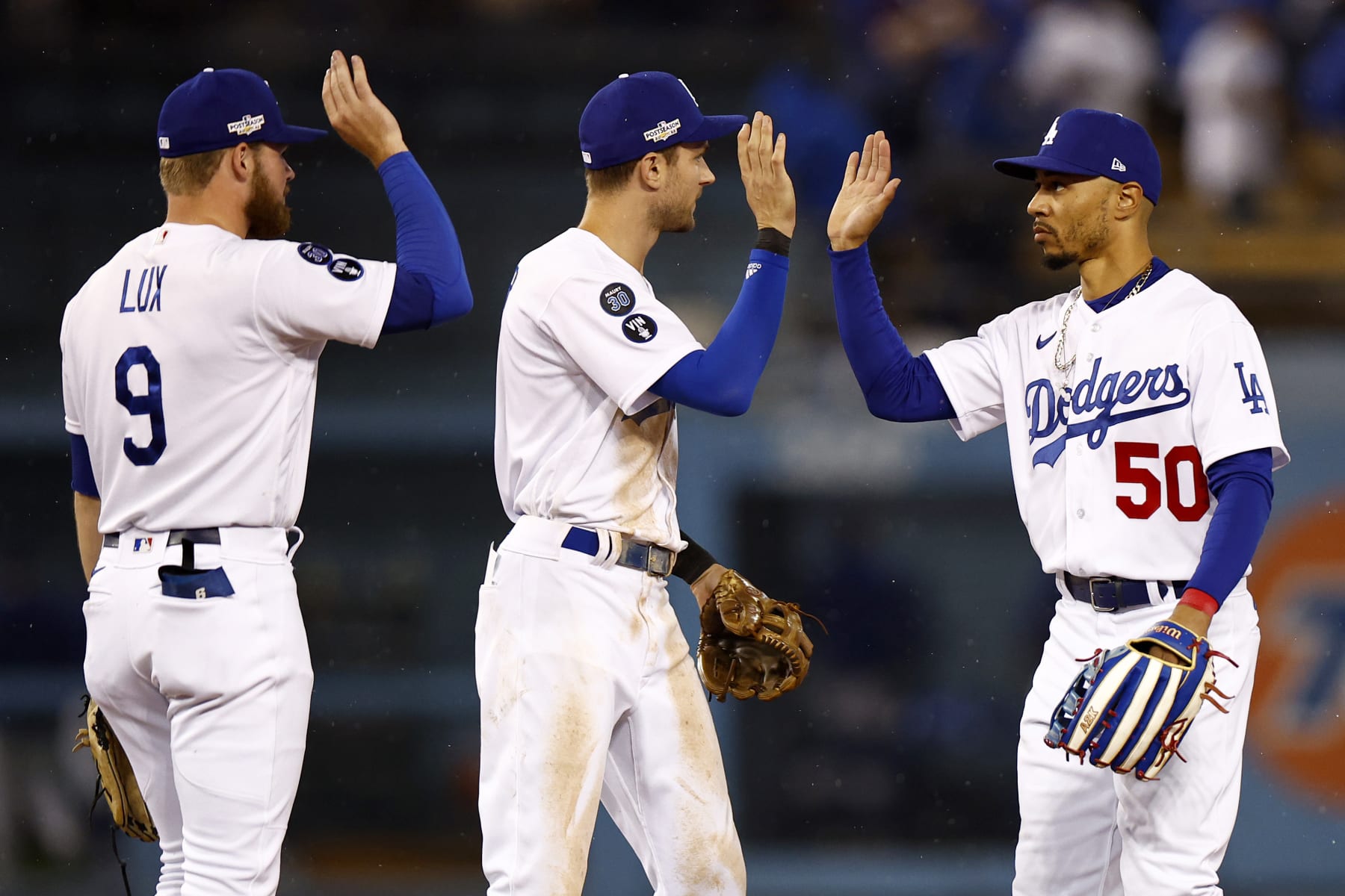 LOS ANGELES, CALIFORNIA - OCTOBER 11: Mookie Betts #50 high fives Trea Turner #6 and Gavin Lux #9 of the Los Angeles Dodgers after a 5-3 win over the San Diego Padres in game one of the National League Division Series at Dodger Stadium on October 11, 2022 in Los Angeles, California. (Photo by Ronald Martinez/Getty Images)