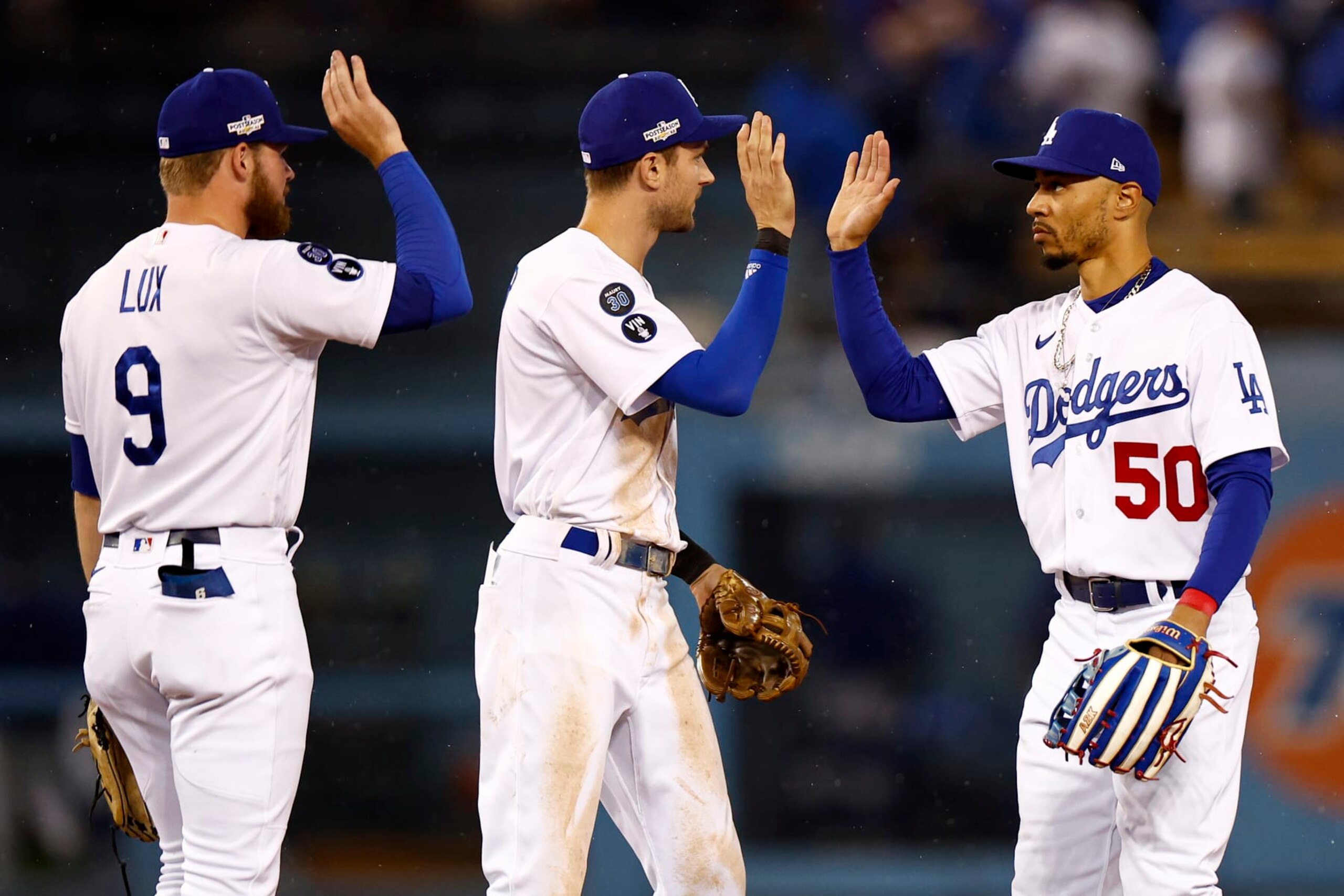 LOS ANGELES, CALIFORNIA - OCTOBER 11: Mookie Betts #50 high fives Trea Turner #6 and Gavin Lux #9 of the Los Angeles Dodgers after a 5-3 win over the San Diego Padres in game one of the National League Division Series at Dodger Stadium on October 11, 2022 in Los Angeles, California. (Photo by Ronald Martinez/Getty Images)
