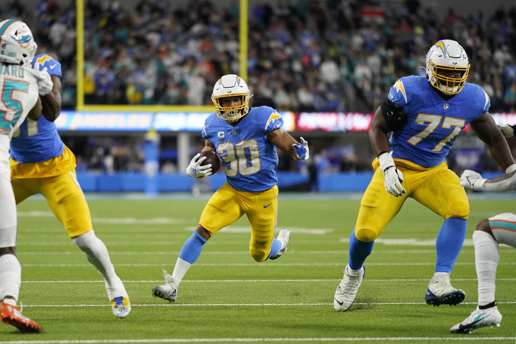 Los Angeles Chargers running back Austin Ekeler (30) runs behind guard Zion Johnson (77) during the first half of an NFL football game against the Miami Dolphins Sunday, Dec. 11, 2022, in Inglewood, Calif. (AP Photo/Jae C. Hong)