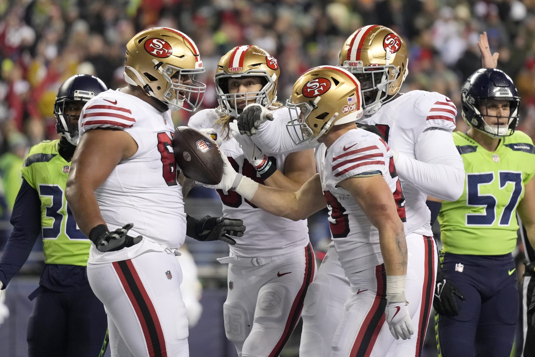 San Francisco 49ers running back Christian McCaffrey, middle right, is congratulated by teammates after scoring against the Seattle Seahawks during the first half of an NFL football game in Seattle, Thursday, Dec. 15, 2022. (AP Photo/Stephen Brashear)