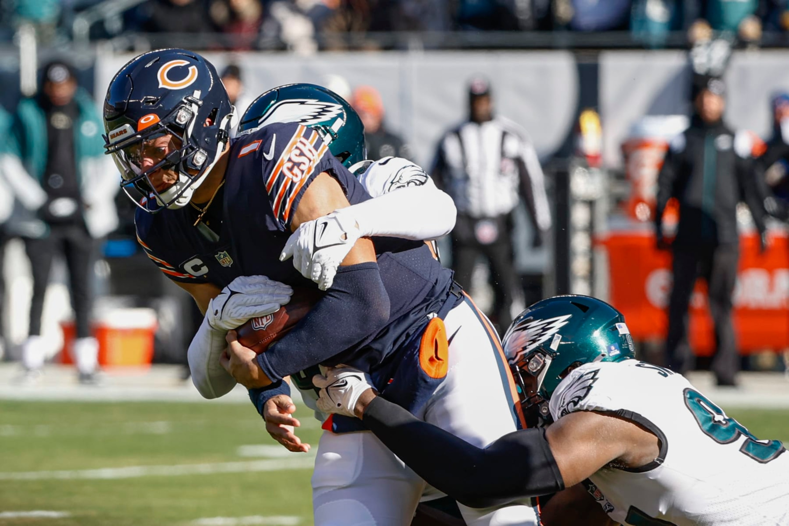 Chicago Bears quarterback Justin Fields, left, is tackled by Philadelphia Eagles linebacker Kyzir White, back, and defensive end Josh Sweat, right, during the first half of an NFL football game, Sunday, Dec. 18, 2022, in Chicago. (AP Photo/Kamil Krzaczynski)