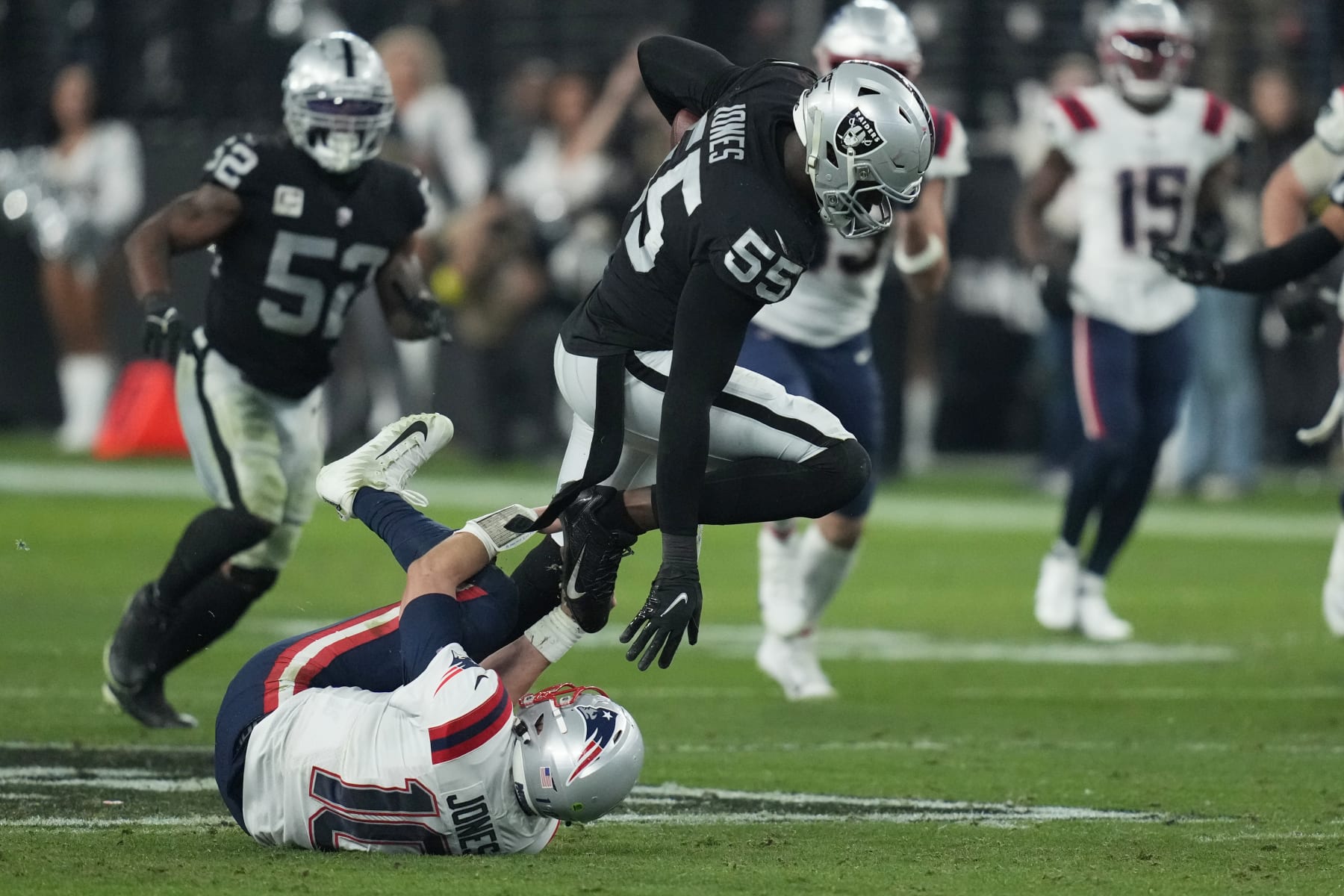 Las Vegas Raiders defensive end Chandler Jones (55) breaks a tackle by New England Patriots quarterback Mac Jones (10) to score a touchdown on an interception during the second half of an NFL football game, Sunday, Dec. 18, 2022, in Las Vegas. (AP Photo/John Locher)