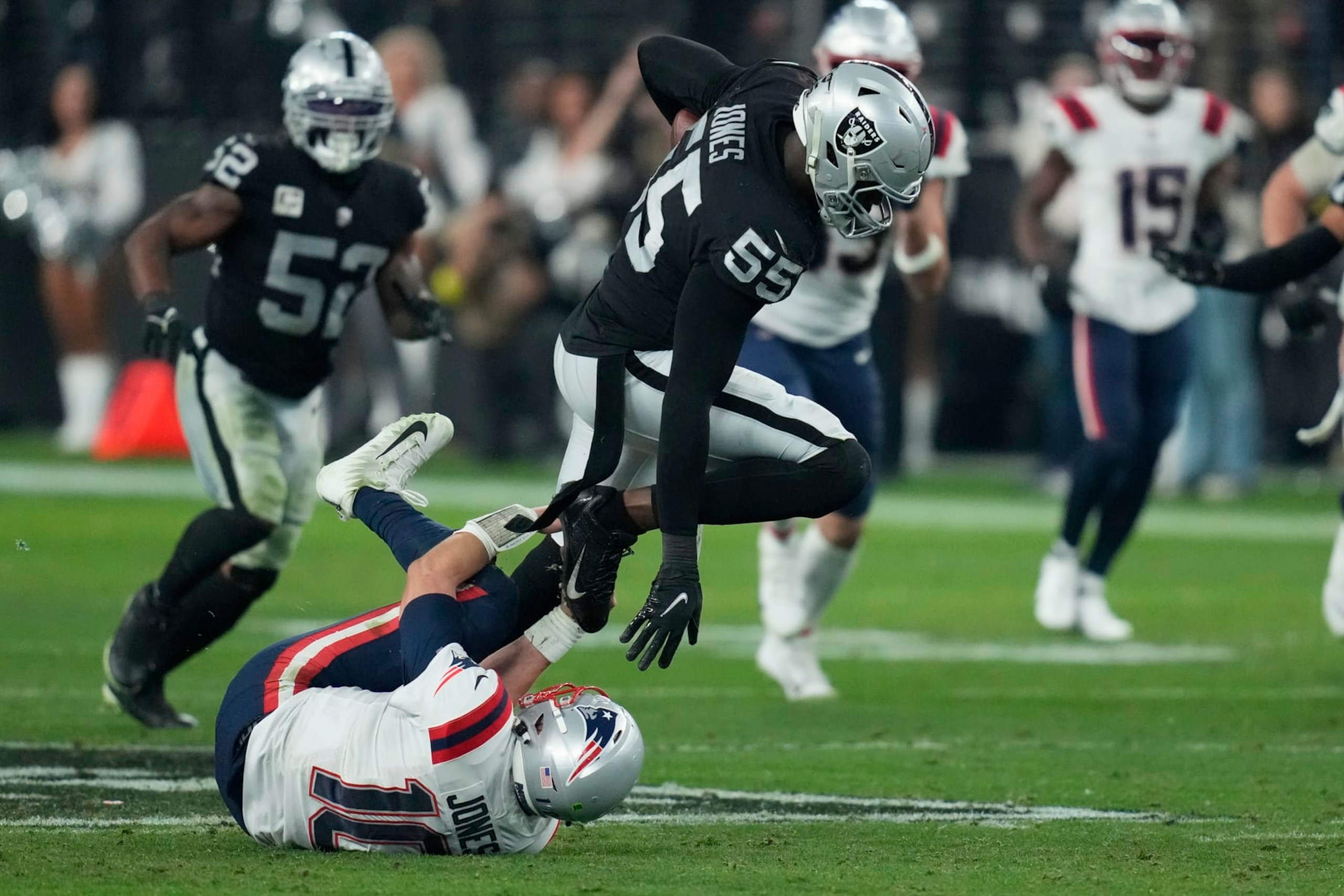 Las Vegas Raiders defensive end Chandler Jones (55) breaks a tackle by New England Patriots quarterback Mac Jones (10) to score a touchdown on an interception during the second half of an NFL football game, Sunday, Dec. 18, 2022, in Las Vegas. (AP Photo/John Locher)
