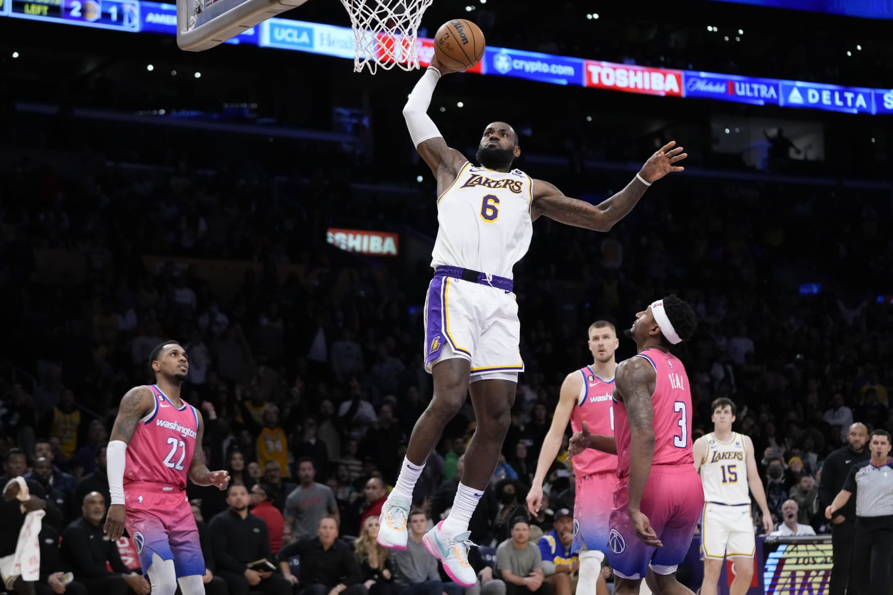 Los Angeles Lakers' LeBron James (6) goes up for a dunk as Washington Wizards' Bradley Beal (3), Monte Morris (22) watch during the second half of an NBA basketball game Sunday, Dec. 18, 2022, in Los Angeles. The Lakers won 119-117. (AP Photo/Jae C. Hong)