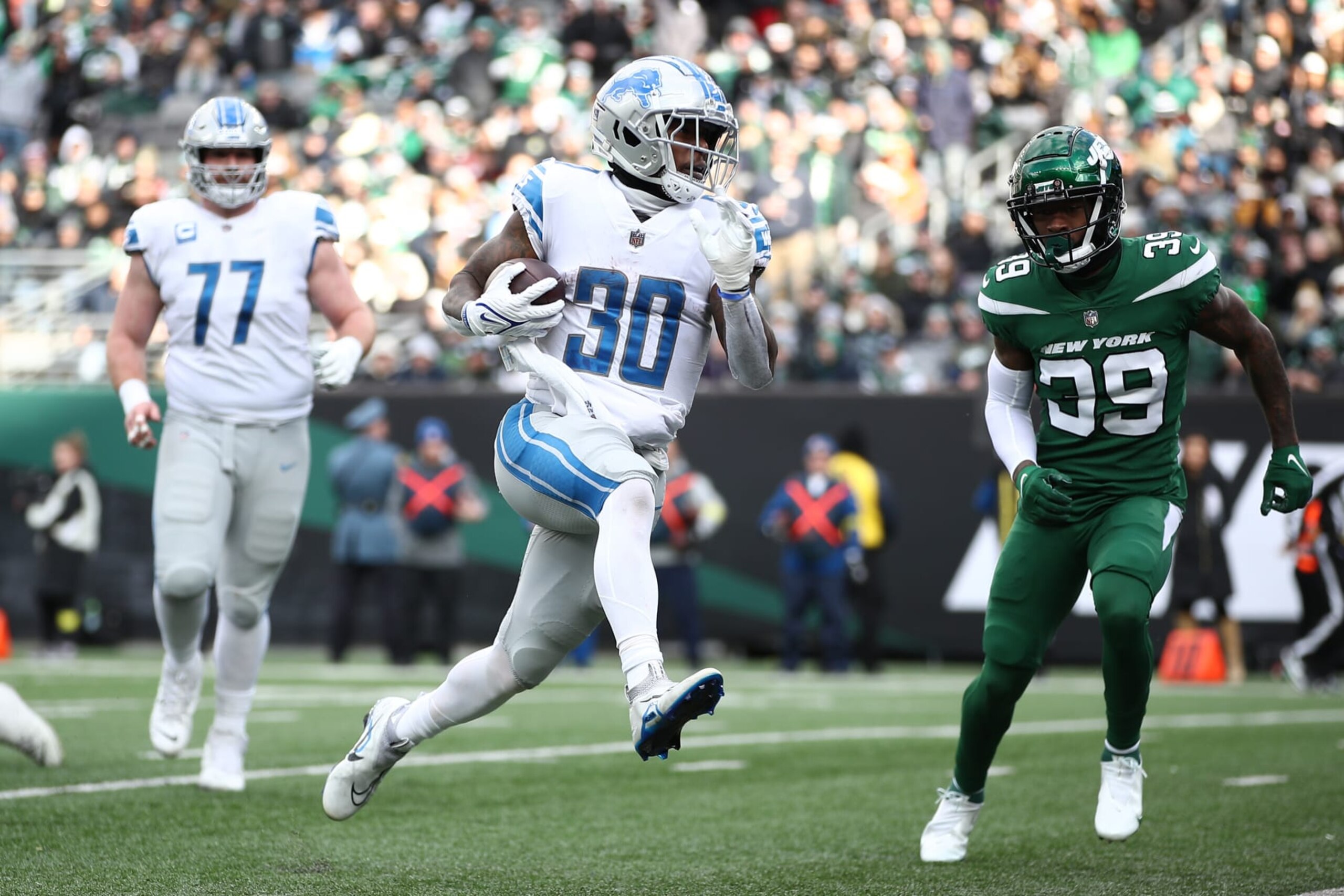 EAST RUTHERFORD, NEW JERSEY - DECEMBER 18: Jamaal Williams #30 of the Detroit Lions runs with the ball as Will Parks #39 of the New York Jets defends at MetLife Stadium on December 18, 2022 in East Rutherford, New Jersey. (Photo by Sarah Stier/Getty Images)