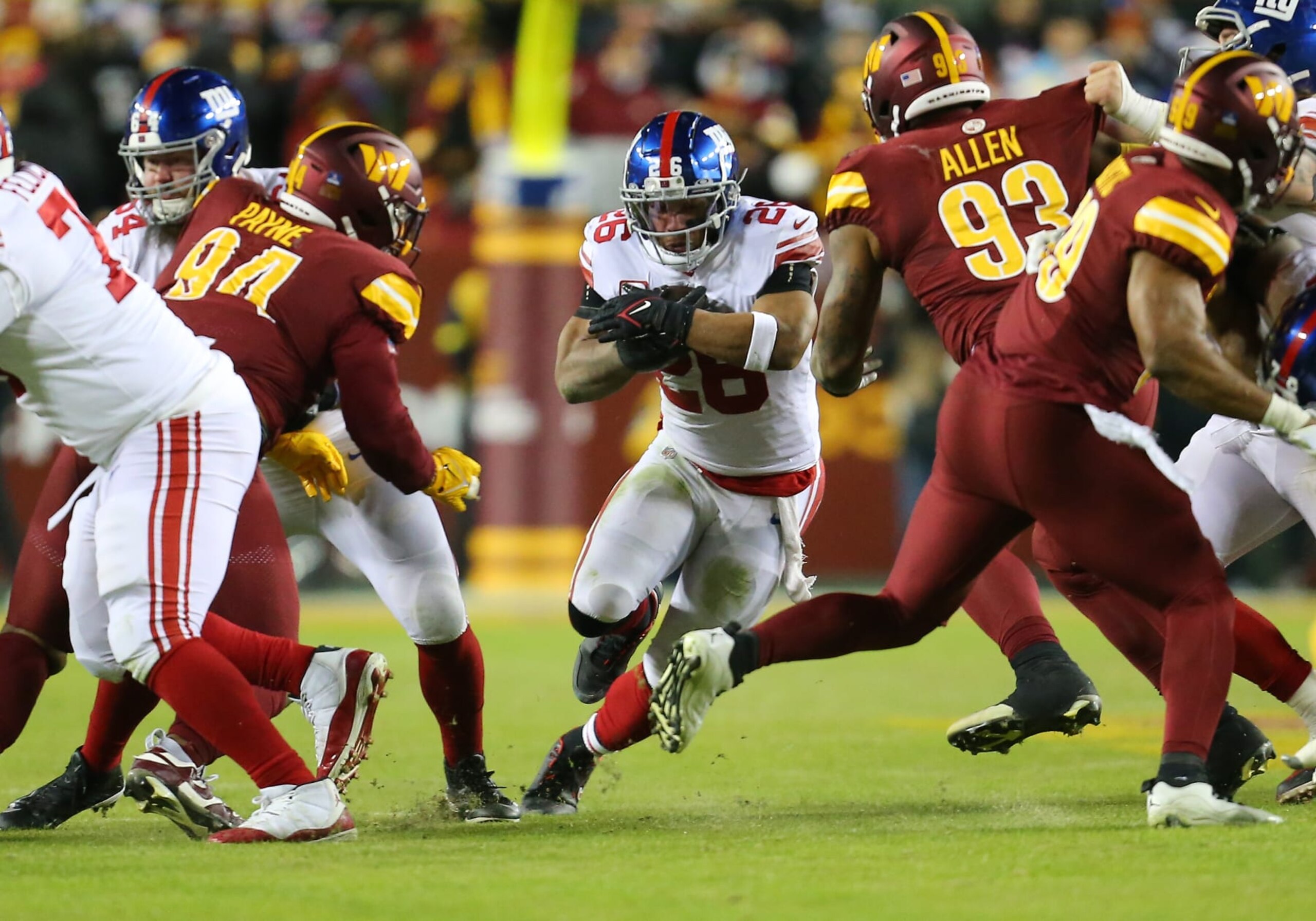 LANDOVER, MD - DECEMBER 18: New York Giants running back Saquon Barkley (26) rushes up field attempting to elude Washington Commanders defensive tackles Jonathan Allen (93) and Daron Payne (94) during the New York Giants game versus the Washington Commanders on December 18, 2022, at FedEx Field in Landover, MD. (Photo by Lee Coleman/Icon Sportswire via Getty Images)