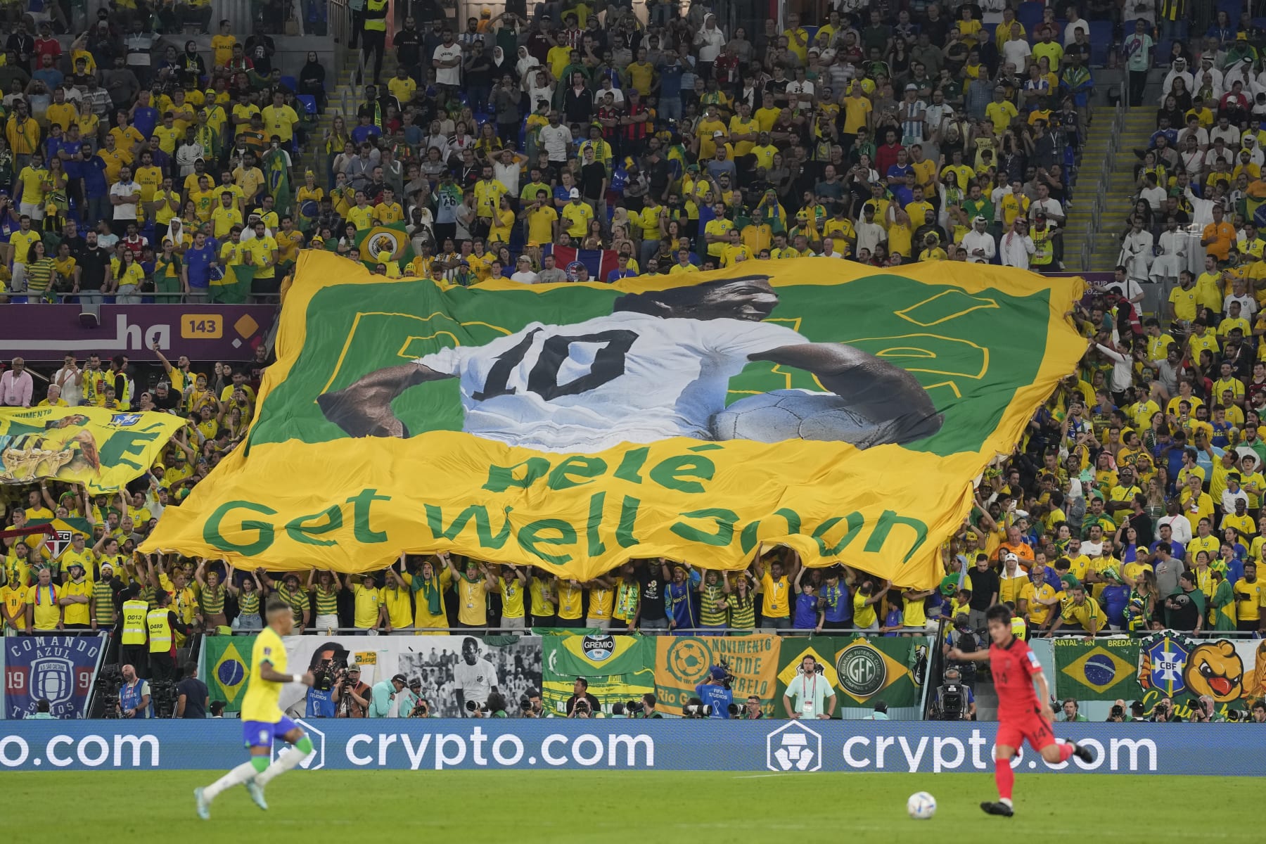 Brazilian fans hold a banner showing the Brazilian soccer legend Pele with the message 'Get well soon' during the World Cup round of 16 soccer match between Brazil and South Korea at the Stadium 974 in Doha, Qatar, Monday, Dec. 5, 2022. Pele is in a hospital in San Paulo recovering from a respiratory infection. (AP Photo/Jin-Man Lee)