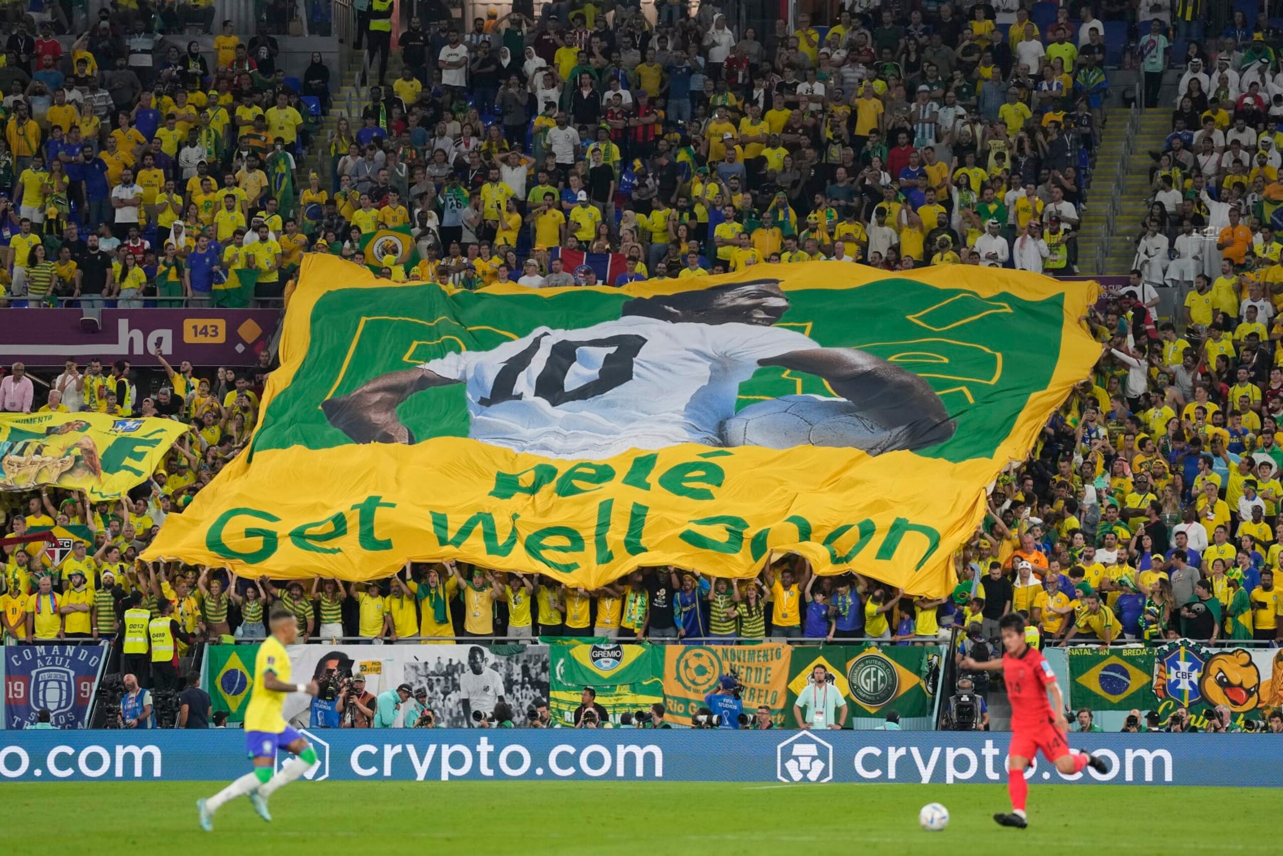 Brazilian fans hold a banner showing the Brazilian soccer legend Pele with the message 'Get well soon' during the World Cup round of 16 soccer match between Brazil and South Korea at the Stadium 974 in Doha, Qatar, Monday, Dec. 5, 2022. Pele is in a hospital in San Paulo recovering from a respiratory infection. (AP Photo/Jin-Man Lee)