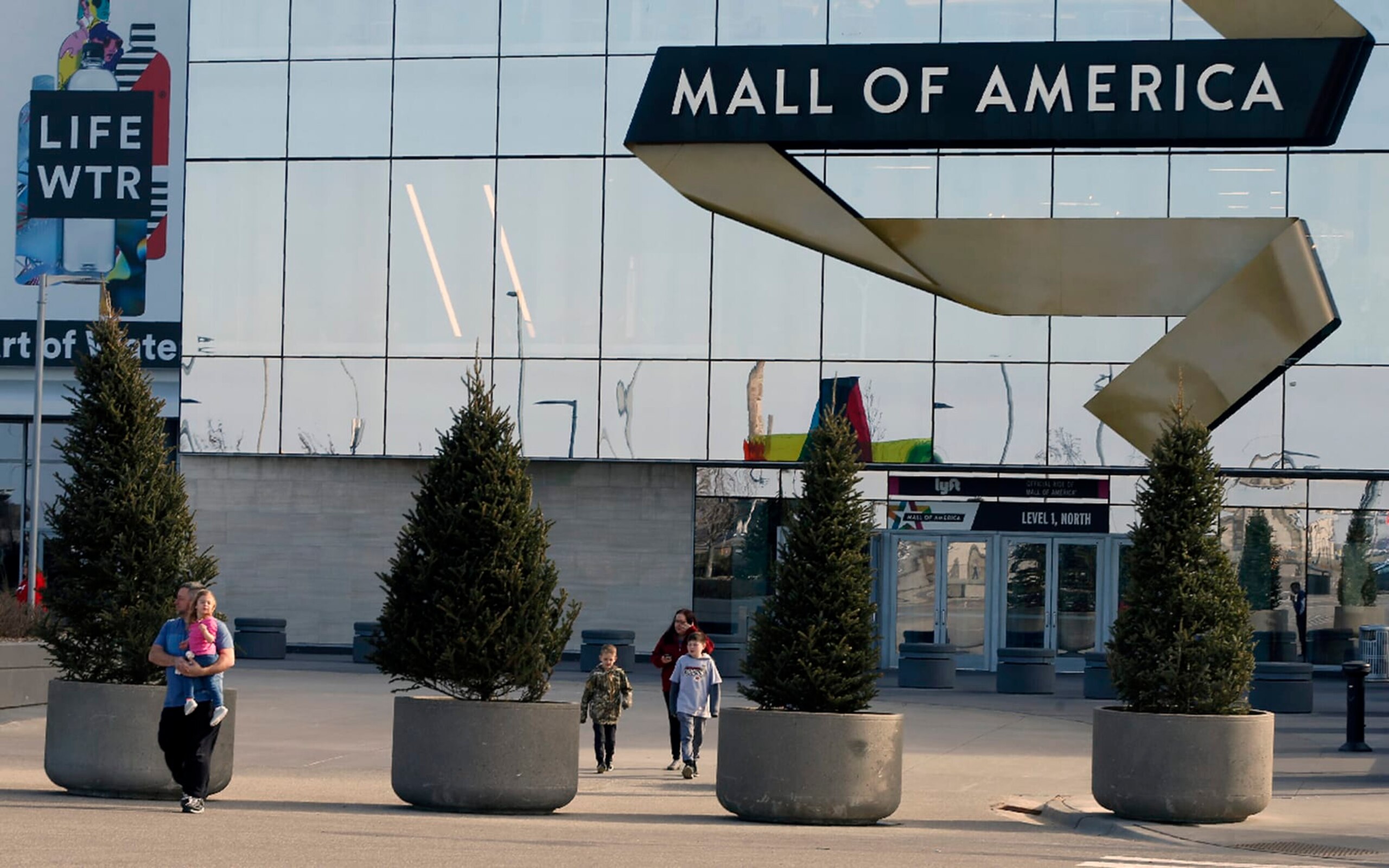 FILE - Shoppers, visitors and employees exit the Mall of America on March 17, 2020 as the mall in Bloomington, Minn. The family of a boy who was severely injured when he was thrown off a third-floor balcony at the Mall of America in April 2019 has reached a confidential settlement with the shopping center, which includes making changes to its trespassing policies, the family and mall announced Monday, Dec. 5, 2022. (AP Photo/Jim Mone, File)