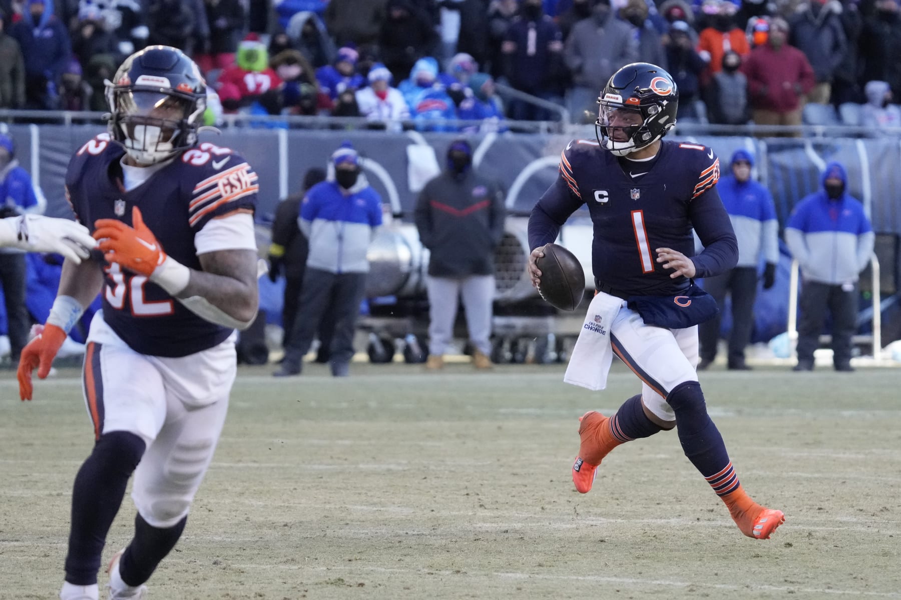 Chicago Bears quarterback Justin Fields, right, runs as he looks to pass against the Buffalo Bills during the second half of an NFL football game, Saturday, Dec. 24, 2022, in Chicago. The Bills won 35-13. (AP Photo/Nam Y. Huh)