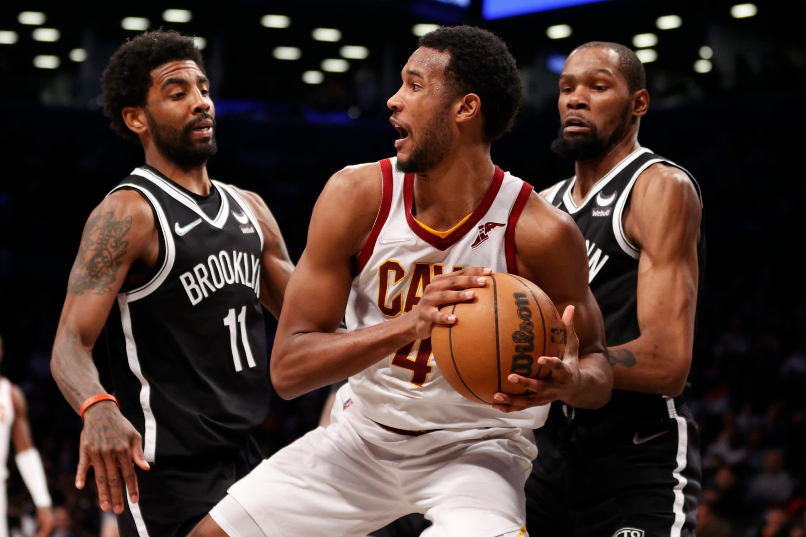 NEW YORK, NEW YORK - APRIL 12: Evan Mobley #4 of the Cleveland Cavaliers looks to pass as Kyrie Irving #11 and Kevin Durant #7 of the Brooklyn Nets defend during the second half of the Eastern Conference 2022 Play-In Tournament at Barclays Center on April 12, 2022 in the Brooklyn borough of New York City. The Nets won 115-108. NOTE TO USER: User expressly acknowledges and agrees that, by downloading and or using this photograph, User is consenting to the terms and conditions of the Getty Images License Agreement. (Photo by Sarah Stier/Getty Images)
