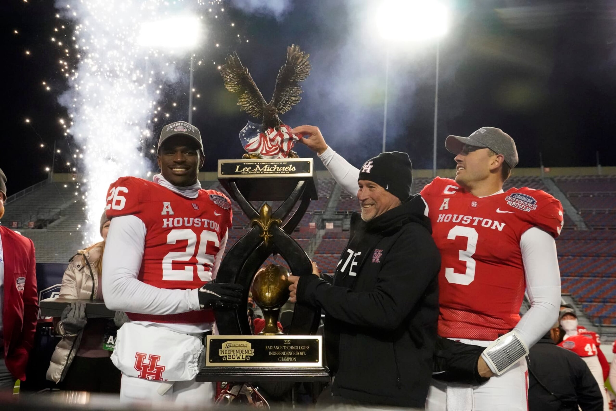CORRECTS TO ART GREEN NOT MOSES ALEXANDER - Houston head coach Dana Holgorsen, center, looks on as he and defensive back Art Green (26) and quarterback Clayton Tune (3) hoist the Independence Bowl championship trophy following their win over Louisiana-Lafayette in an NCAA college football game Friday, Dec. 23, 2022, in Shreveport, La. (AP Photo/Rogelio V. Solis)