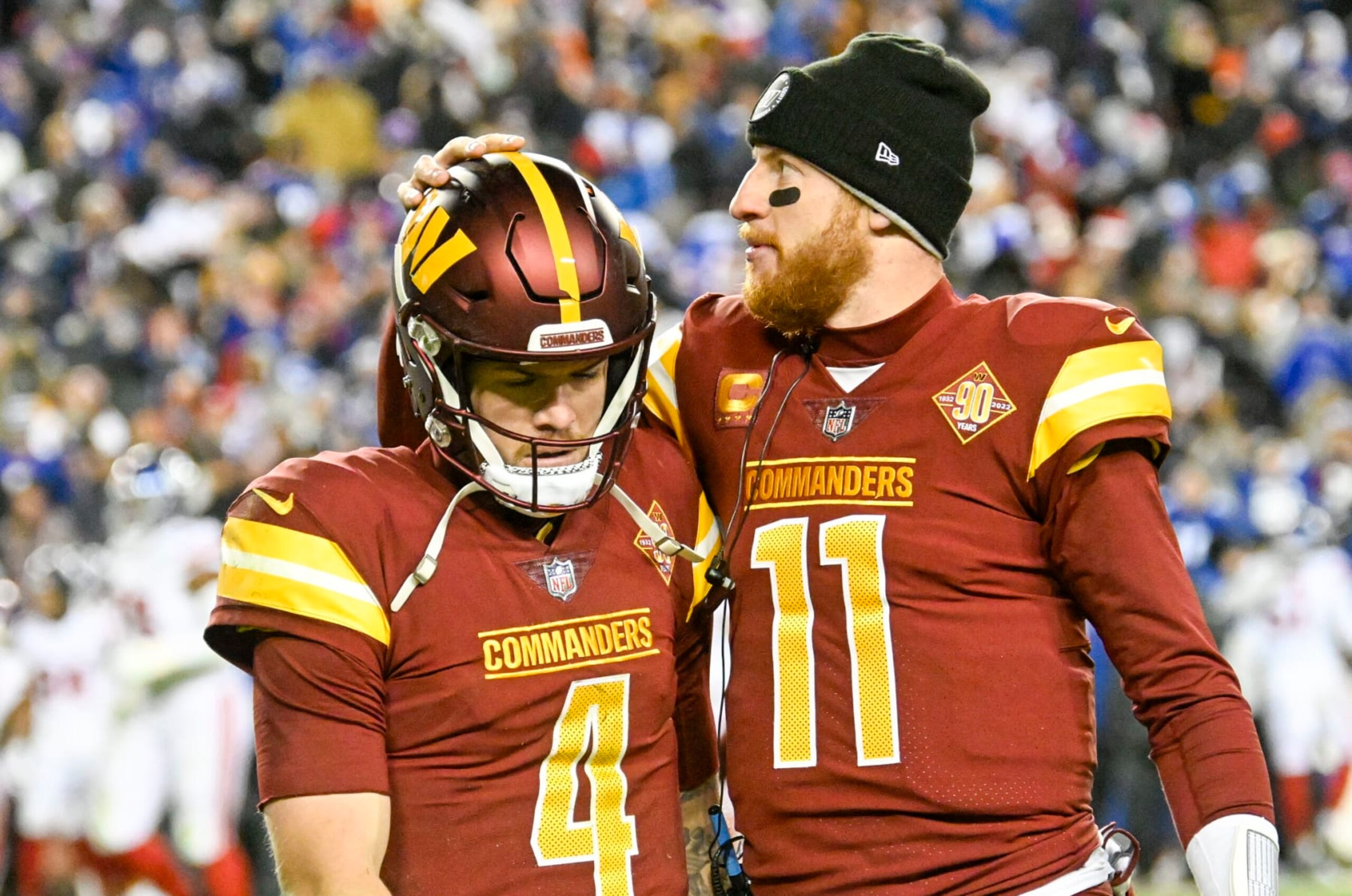 LANDOVER, MD - DECEMBER 18: Washington Commanders backup quarterback Carson Wentz (11) gives quarterback Taylor Heinicke (4) a pat on the head as he watches the replay of their final play during their loss to the New York Giants during the game at FedEx Field on December 18, 2022. (Photo by Jonathan Newton/The Washington Post via Getty Images)