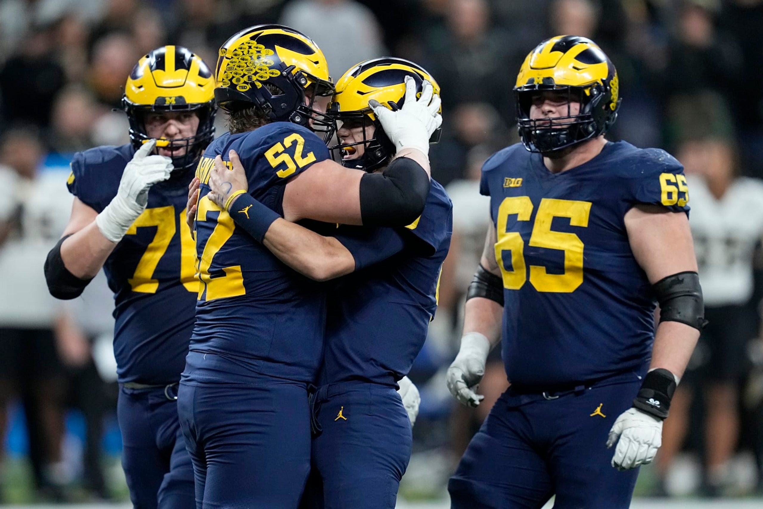 Michigan quarterback J.J. McCarthy is congratulated by teammates Kechaun Bennett (52), Ryan Hayes, left, and Zak Zinter (65) after throwing a touchdown pass during the second half of the Big Ten championship NCAA college football game against Purdue, Saturday, Dec. 3, 2022, in Indianapolis. (AP Photo/Darron Cummings)
