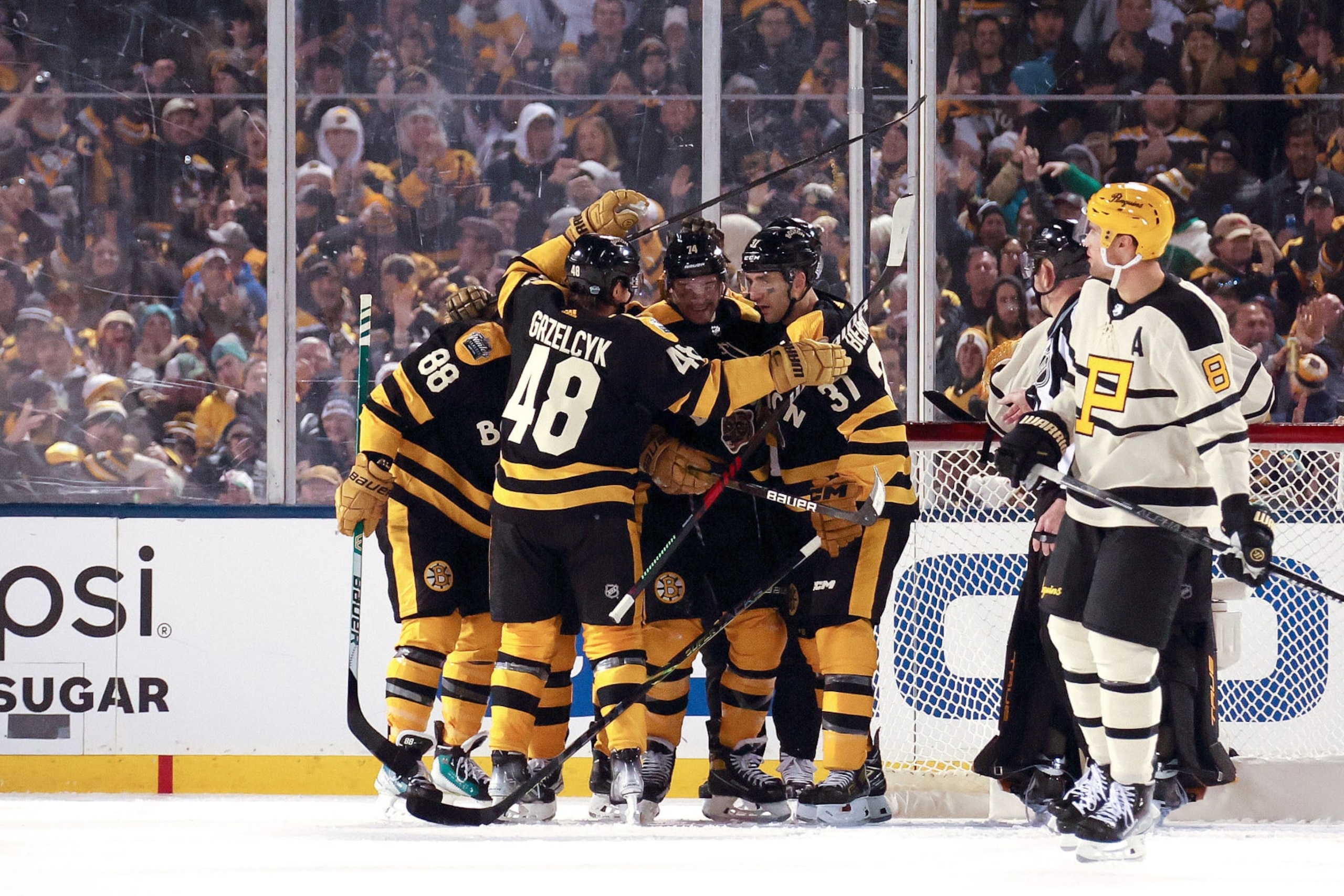 BOSTON, MASSACHUSETTS - JANUARY 02: Jake DeBrusk #74 of the Boston Bruins celebrates with teammates after scoring a goal against the Pittsburgh Penguins during the third period in the 2023 Discover NHL Winter Classic at Fenway Park on January 02, 2023 in Boston, Massachusetts. (Photo by Gregory Shamus/Getty Images) BOSTON, MASSACHUSETTS - JANUARY 02: Jake DeBrusk #74 of the Boston Bruins celebrates with teammates after scoring a goal against the Pittsburgh Penguins during the third period in the 2023 Discover NHL Winter Classic at Fenway Park on January 02, 2023 in Boston, Massachusetts. (Photo by Gregory Shamus/Getty Images)